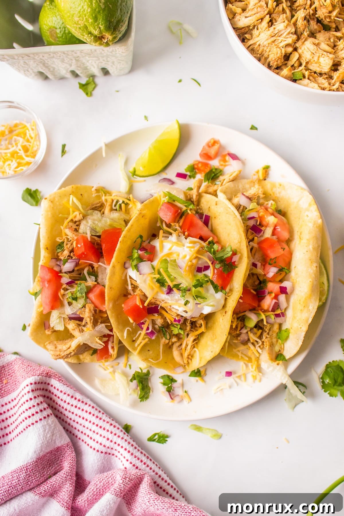 Three beautifully assembled leftover turkey tacos on a white plate, garnished with fresh cilantro and a lime wedge, ready to be enjoyed.