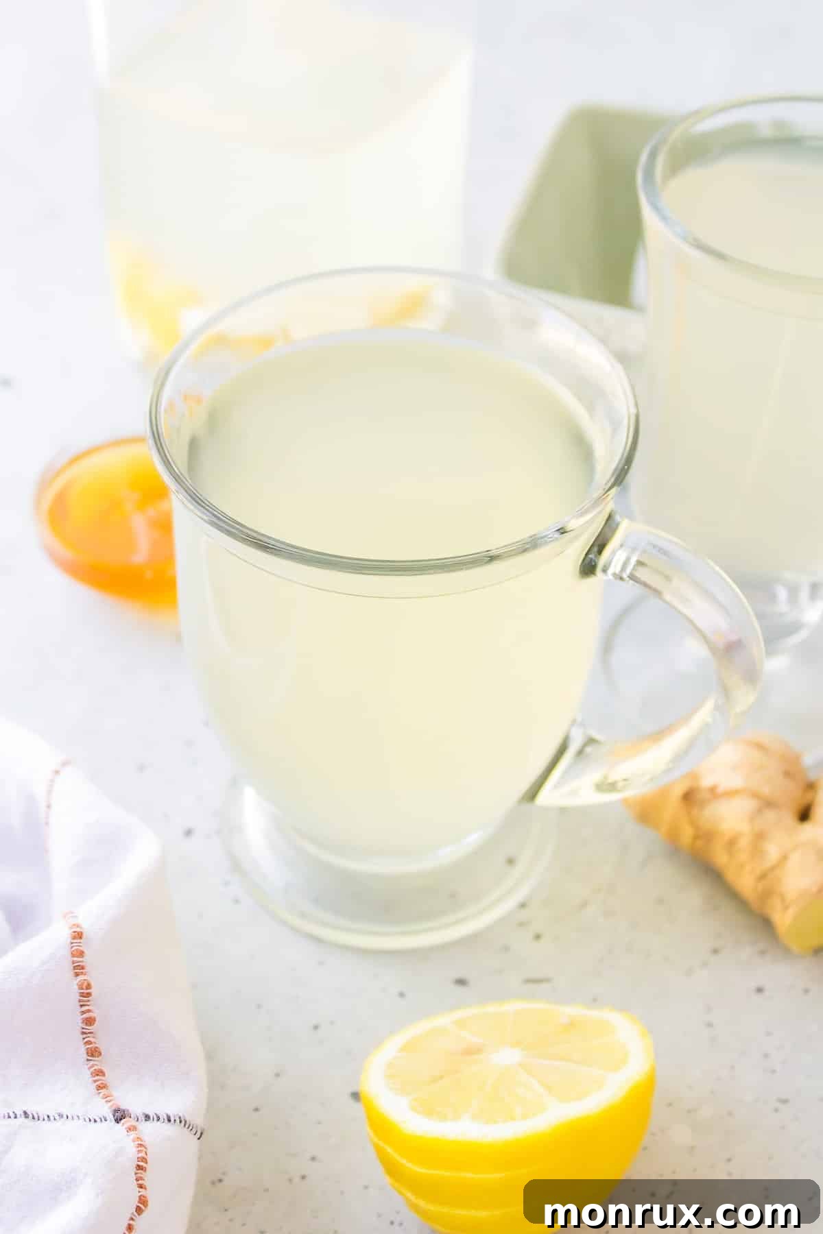 A steaming glass of homemade garlic tea, garnished with a lemon slice and fresh ginger.