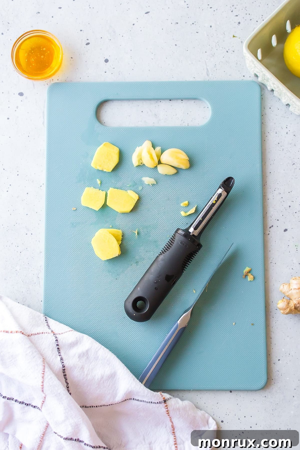 Close-up of fresh ginger and garlic cloves being peeled and sliced on a wooden cutting board, ready for tea preparation.