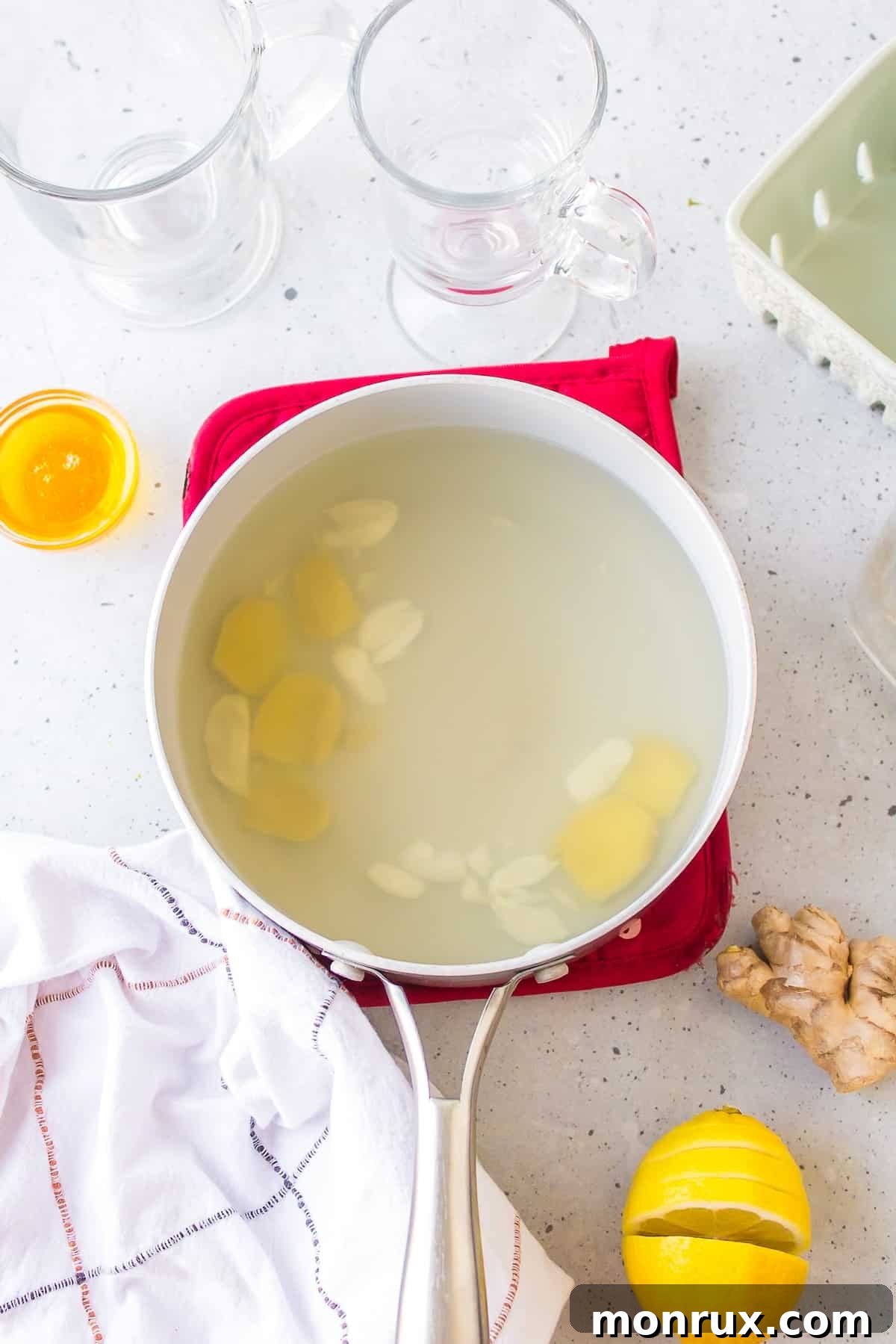 A pot of water on the stove, with sliced ginger and crushed garlic simmering gently inside, creating a fragrant brew.