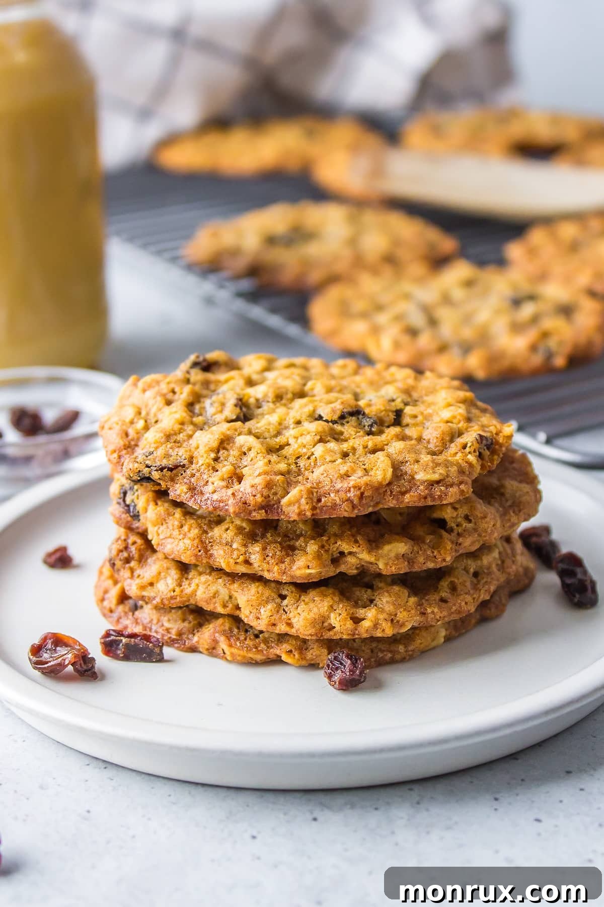 Four oatmeal cookies stacked on a white plate, showcasing their golden-brown edges and soft centers.