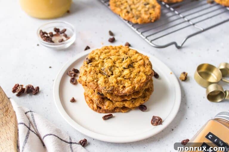 Four oatmeal cookies stacked on a white plate, ready to be enjoyed.