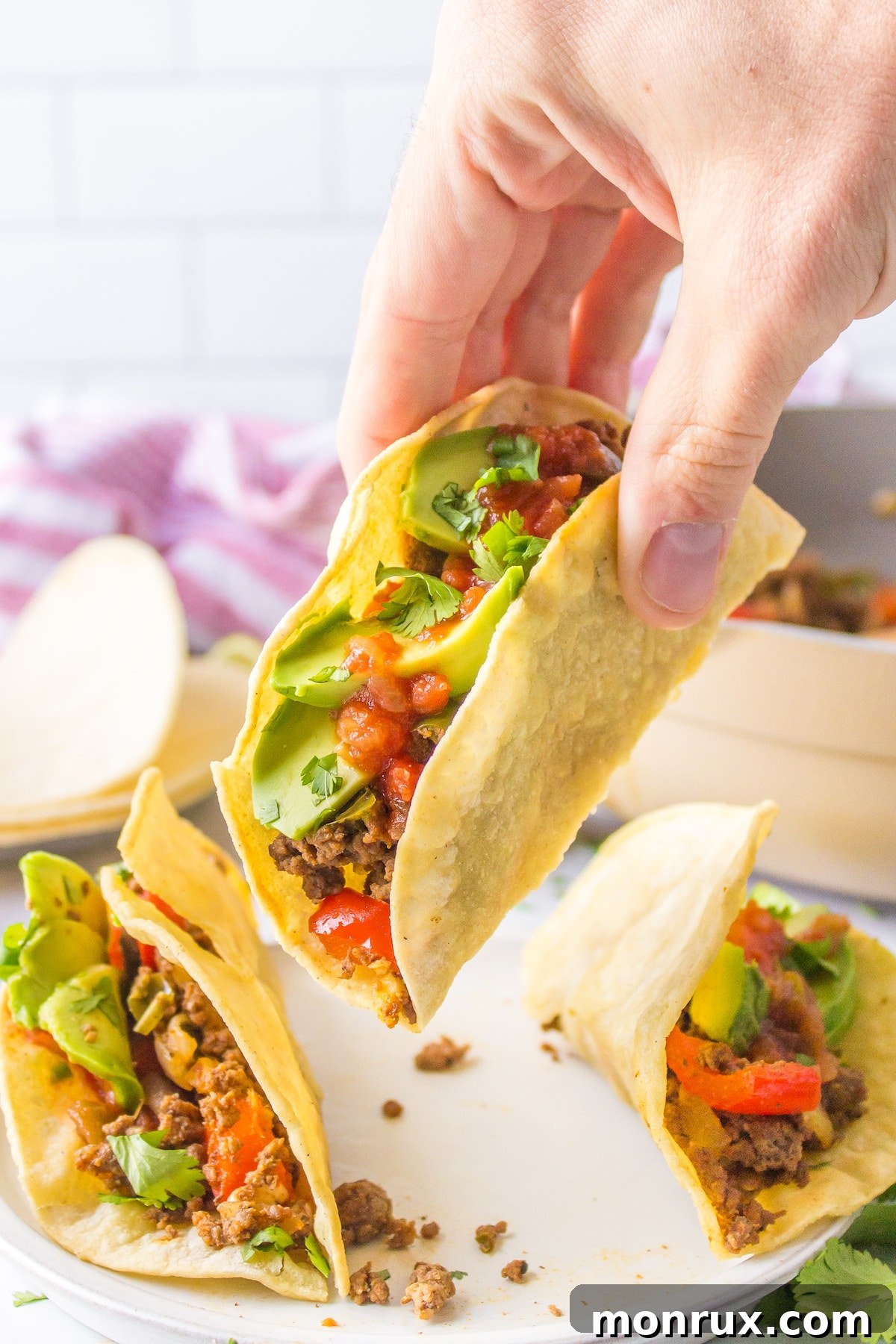 a person holding a bison taco up off of a plate, showing the rich filling.