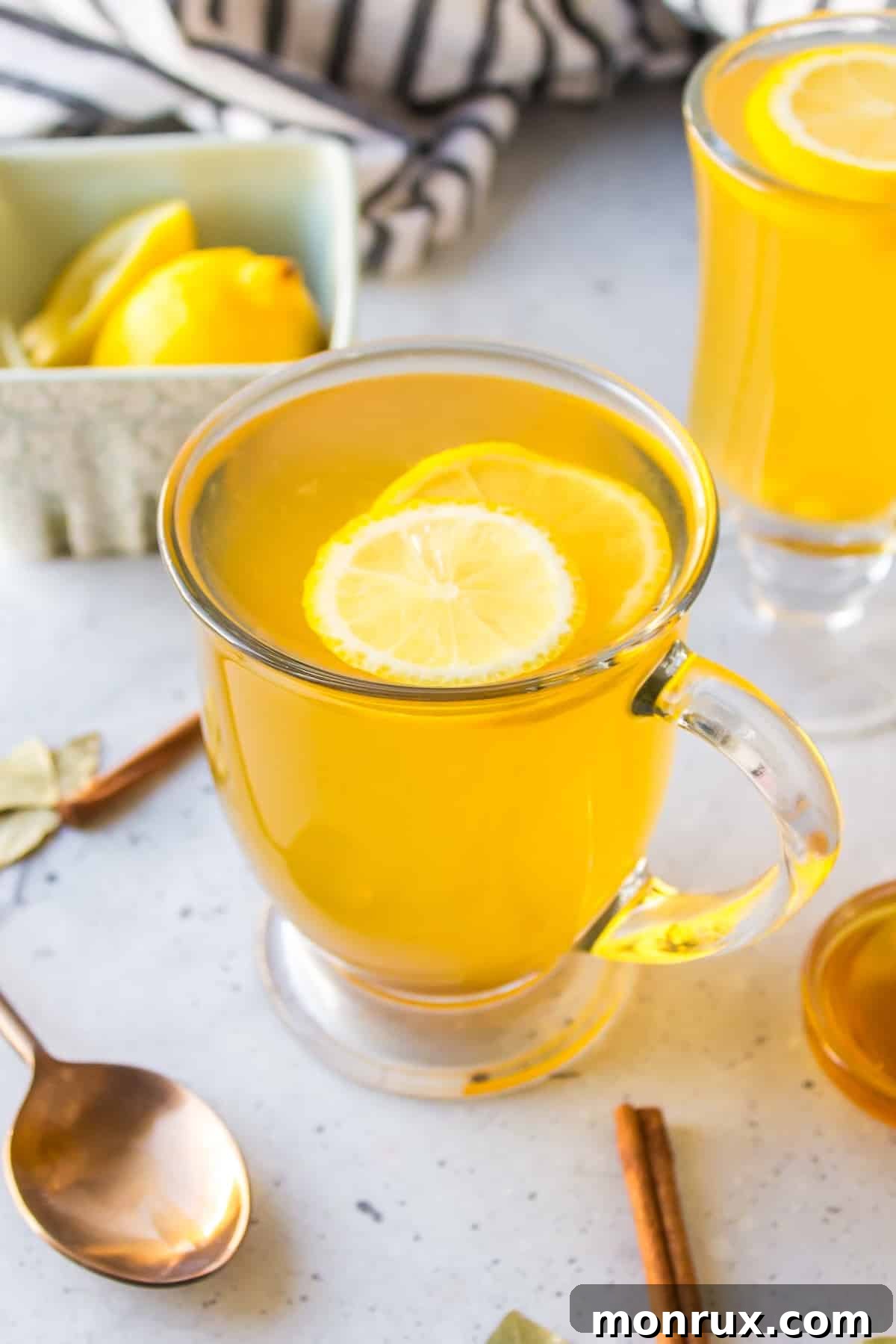 a glass of cinnamon and bay leaf tea with fresh lemon slice on top.