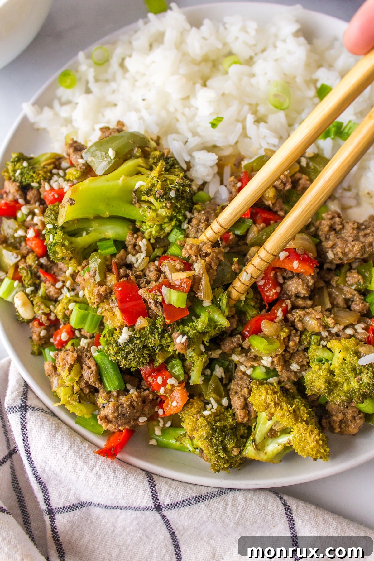 Chopsticks delicately picking up a portion of flavorful bison stir-fry from a serving plate, highlighting its deliciousness.