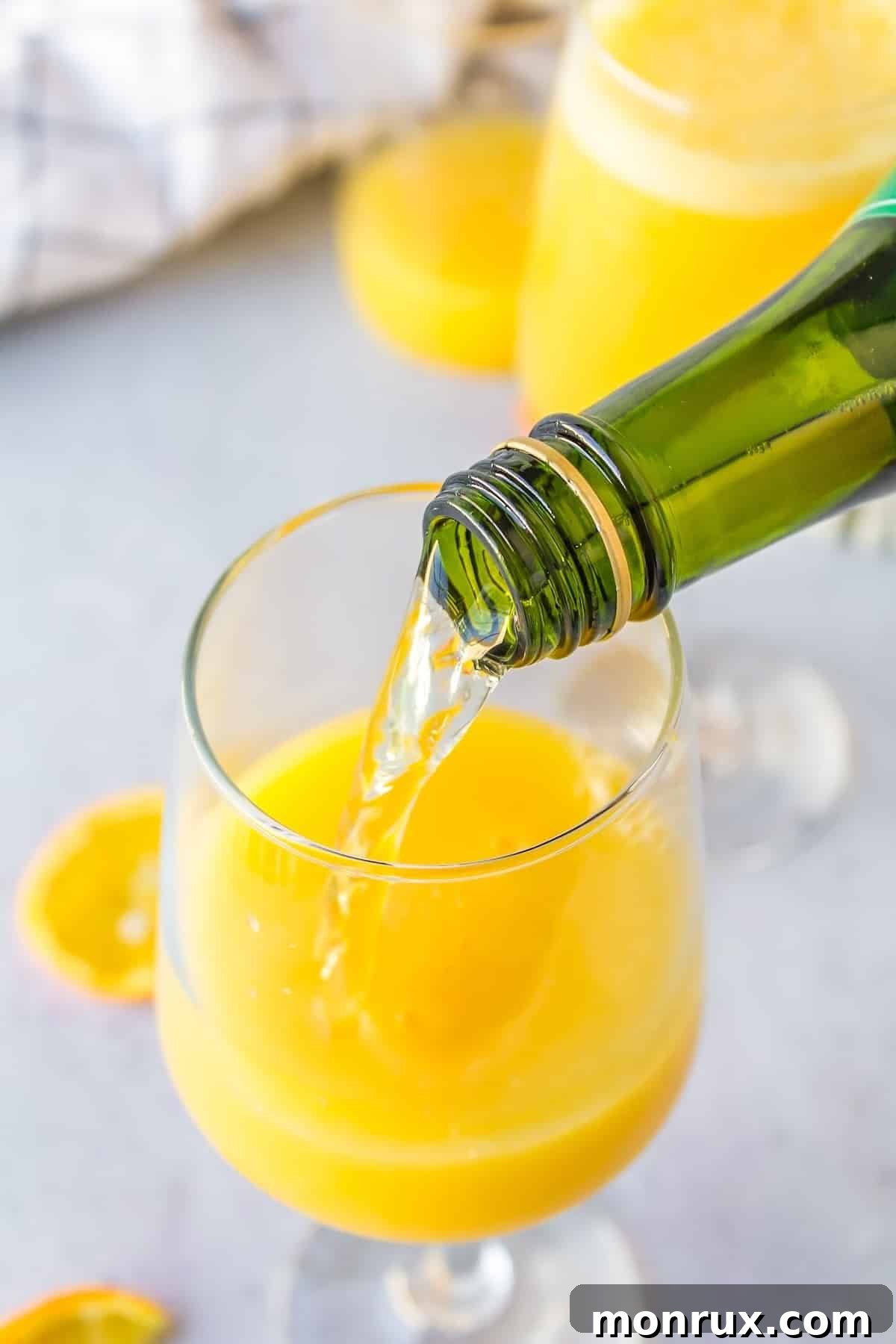 Sparkling juice being carefully poured into a champagne flute, ready to mix with orange juice for a mimosa mocktail.