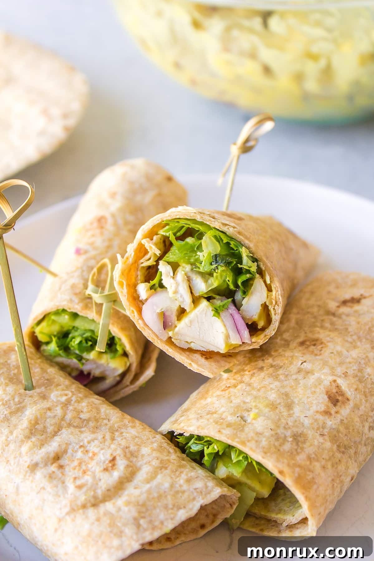 Two Honey Mustard Chicken Wraps, cut in half, presented on a white plate with a fork and a small bowl of extra honey mustard dressing.