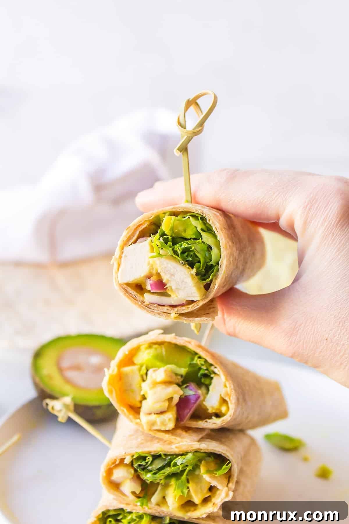 A person holding a freshly made honey mustard chicken wrap, showcasing its appealing filling and readiness to eat.