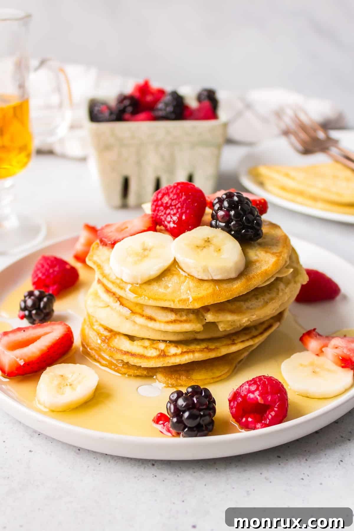 A beautifully arranged plate of dairy-free pancakes, generously topped with golden syrup and fresh, vibrant fruits, promising a delightful start to the day.