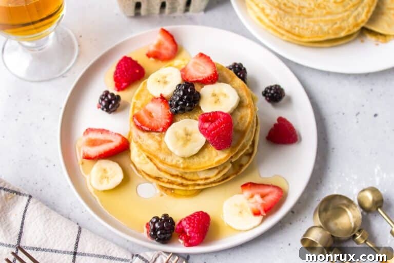 A plate of dairy-free pancakes topped with syrup and fruit.