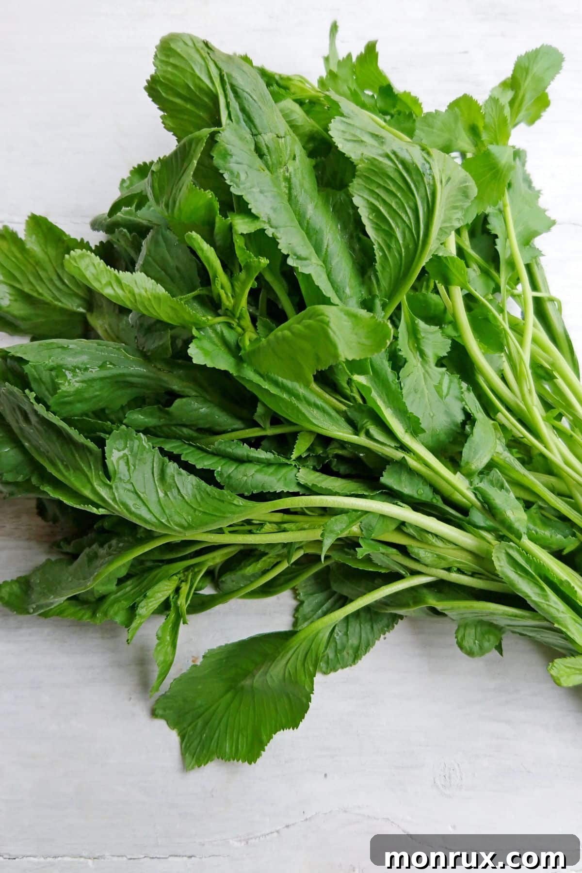 A vibrant bunch of fresh watercress stems gathered on a rustic wooden table, ready for use in cooking or garnishing.