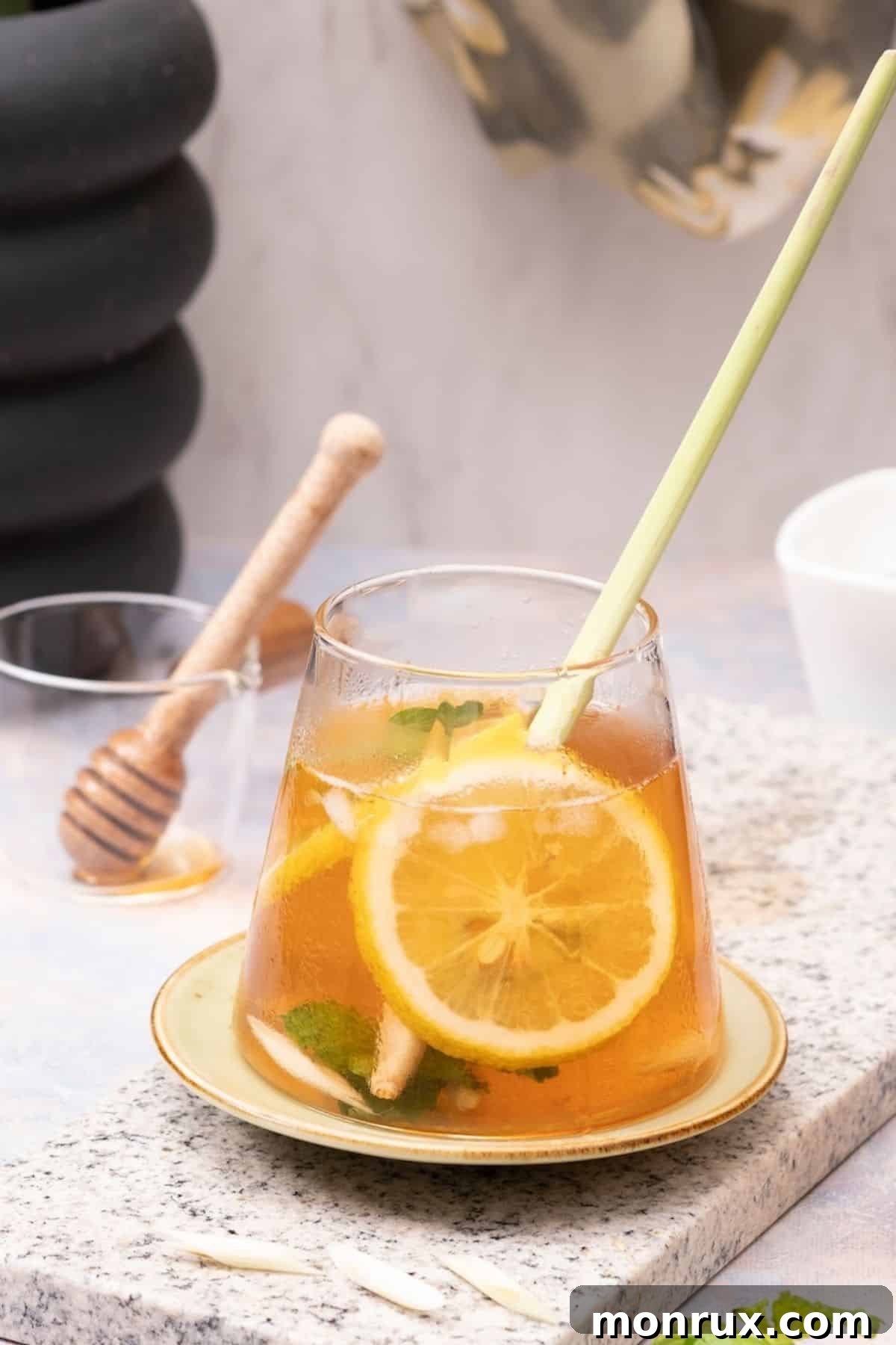 A glass of vibrant lemongrass tea, garnished with fresh mint leaves and bright lemon slices, inviting a moment of refreshing calm.