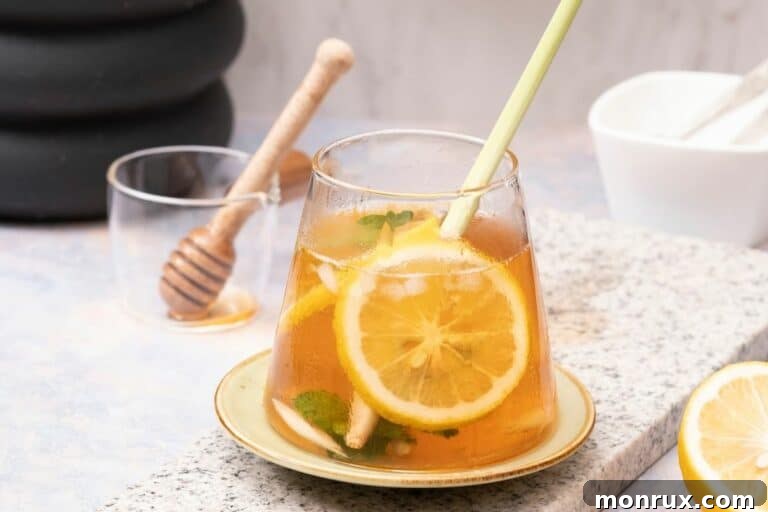 A close-up of a glass of lemongrass tea with mint and lemon slices, showing its fresh and inviting appearance.