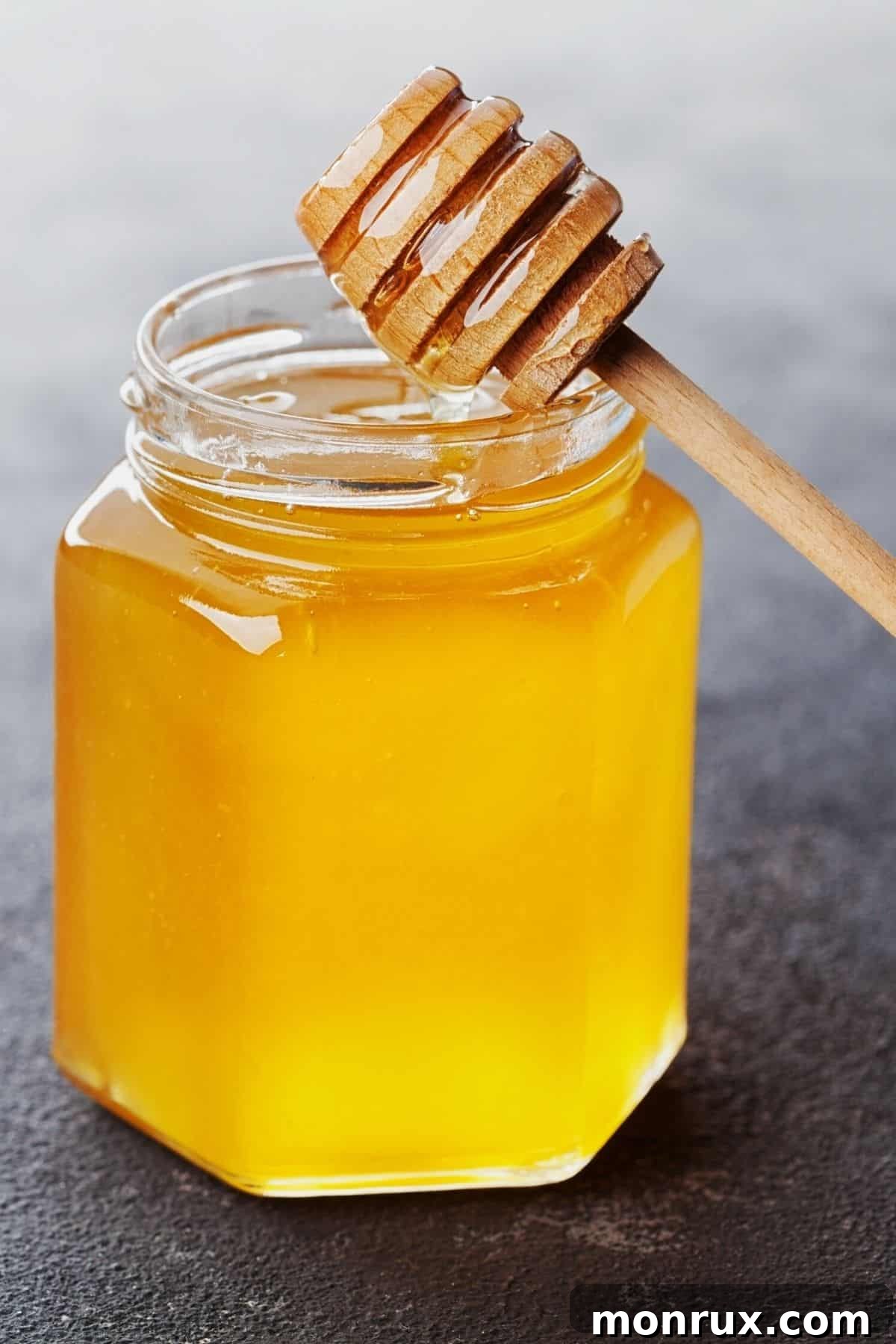A rustic jar of golden honey on a wooden table, with a wooden dipper, evoking warmth and natural goodness.
