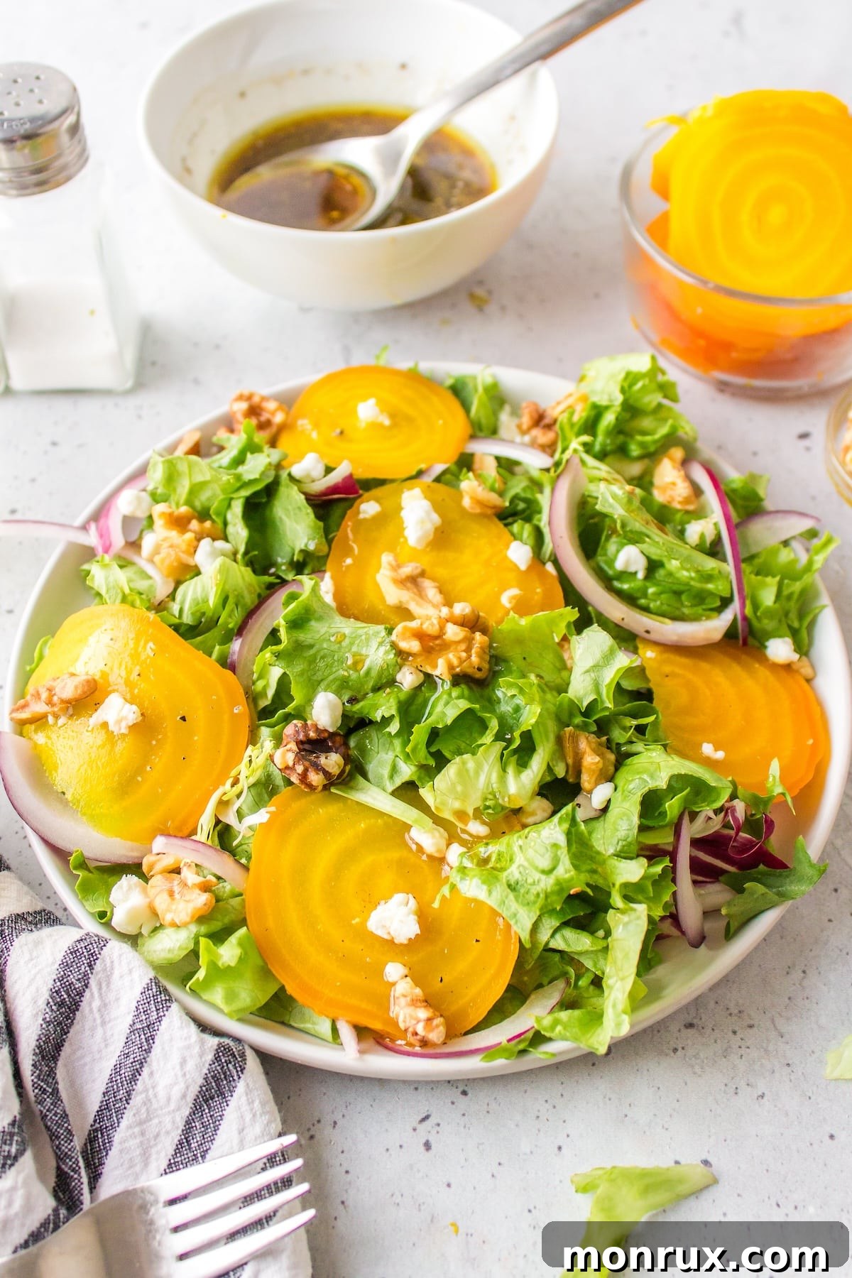 A beautifully plated golden beet salad on a white plate, showcasing vibrant colors and textures.