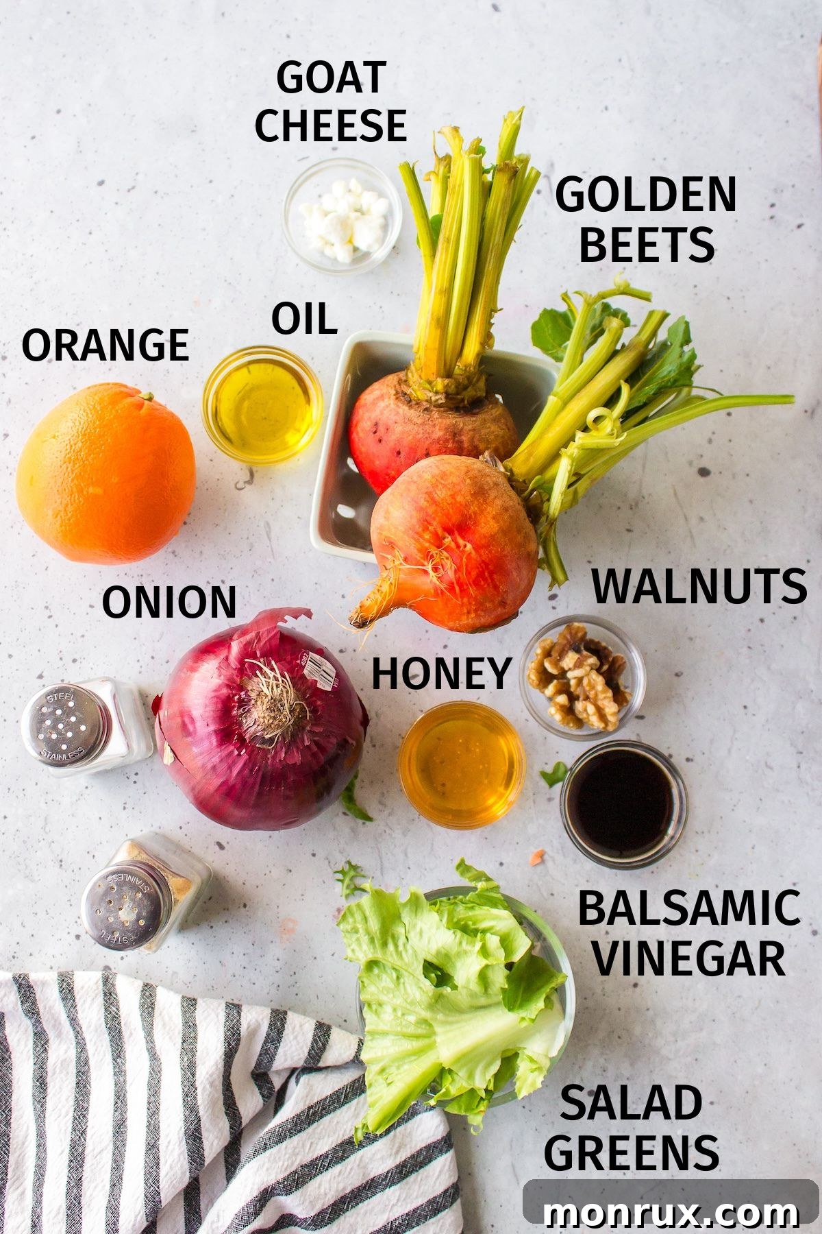Ingredients laid out for a golden beet salad recipe, including golden beets, nuts, greens, and dressing components.