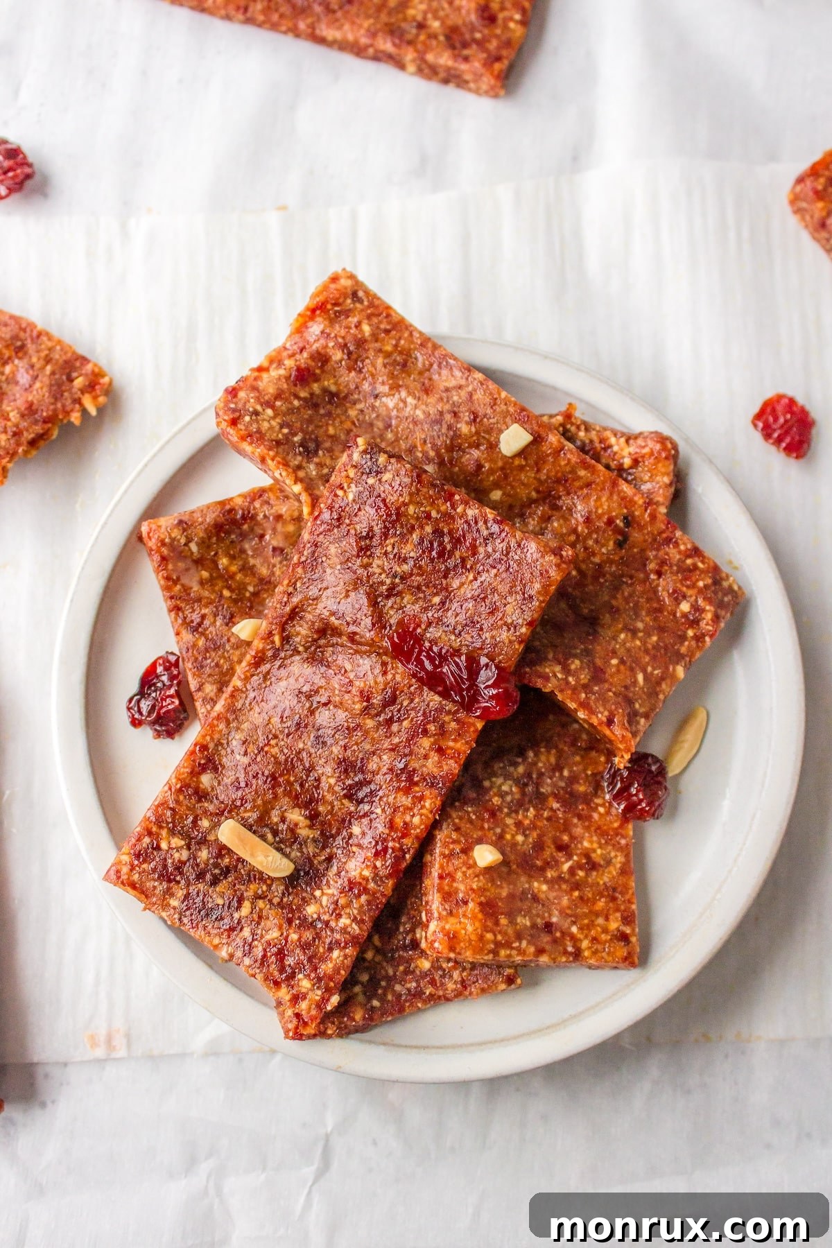 Vibrant almond cherry bars neatly arranged on a pristine white plate, showcasing their inviting texture and rich color.
