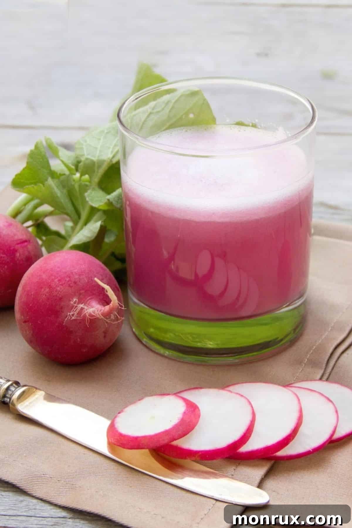 A vibrant glass of homemade radish juice, garnished with fresh mint, sitting beside a bowl of whole and sliced radishes. The scene suggests freshness, health, and a delicious, natural beverage.
