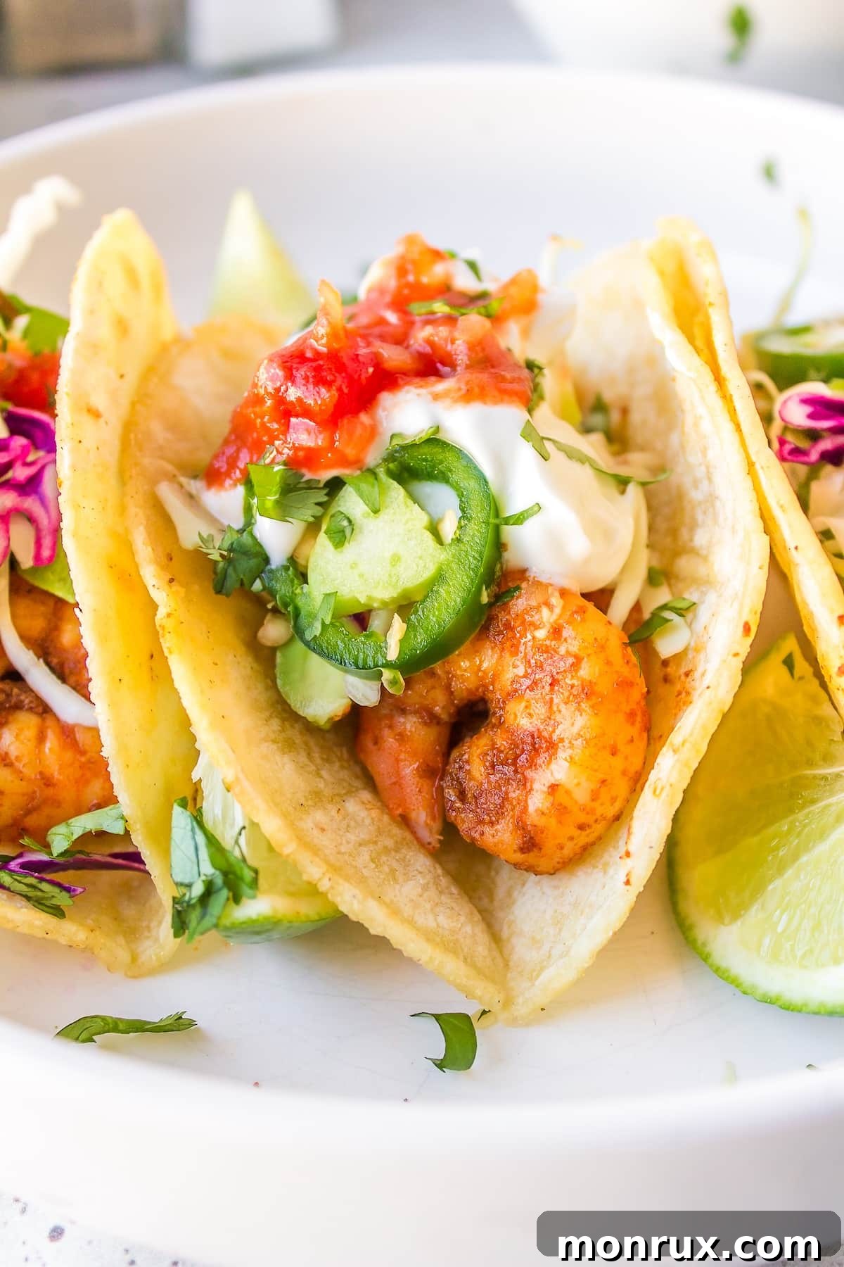A close-up shot of a single Baja Shrimp Taco, highlighting the textures of the shrimp, slaw, and avocado.