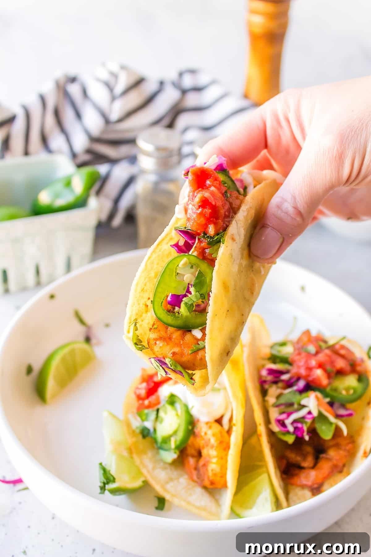 A hand holding a perfectly crafted Baja Shrimp Taco, ready to be enjoyed.