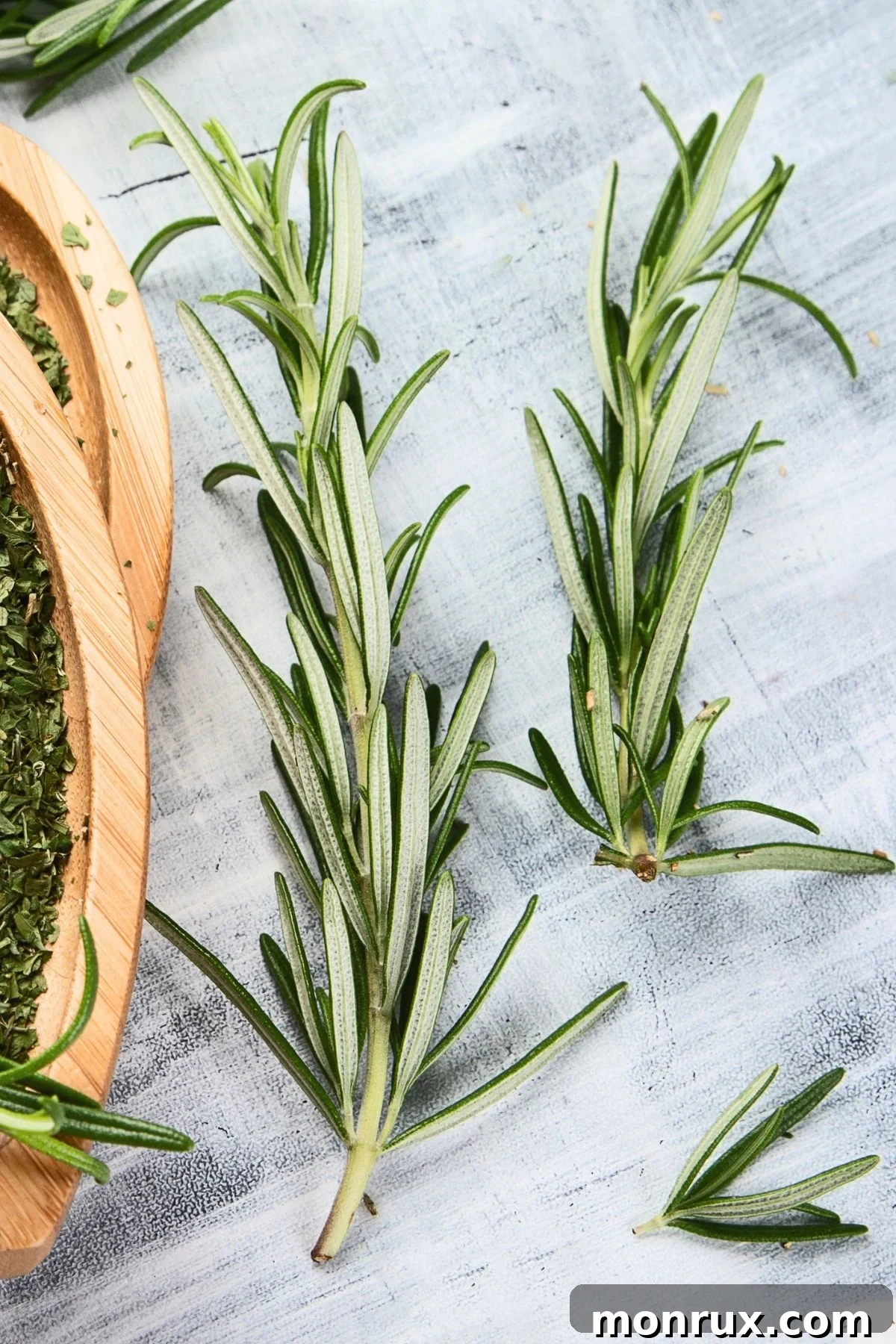 Fresh rosemary sprigs on a white surface.