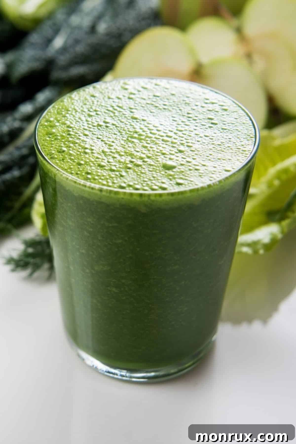 A refreshing glass of green juice, garnished with a slice of lime, sits invitingly on a wooden table. The natural light highlights its vibrant color and fresh ingredients, suggesting a healthy and delicious beverage for any time of day.