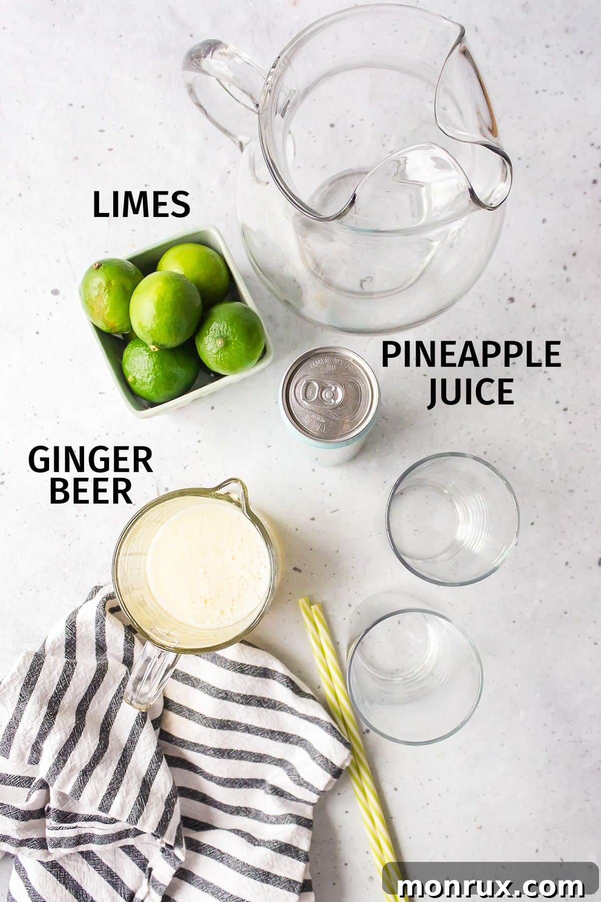 A collection of fresh ingredients including ripe pineapple, zesty limes, and a bottle of non-alcoholic ginger beer, neatly arranged for mocktail preparation.