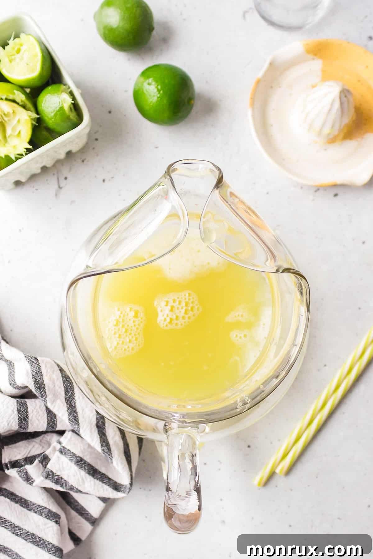 A clear glass pitcher containing the freshly mixed pineapple and lime juices, beautifully golden and ready for the next ingredient.