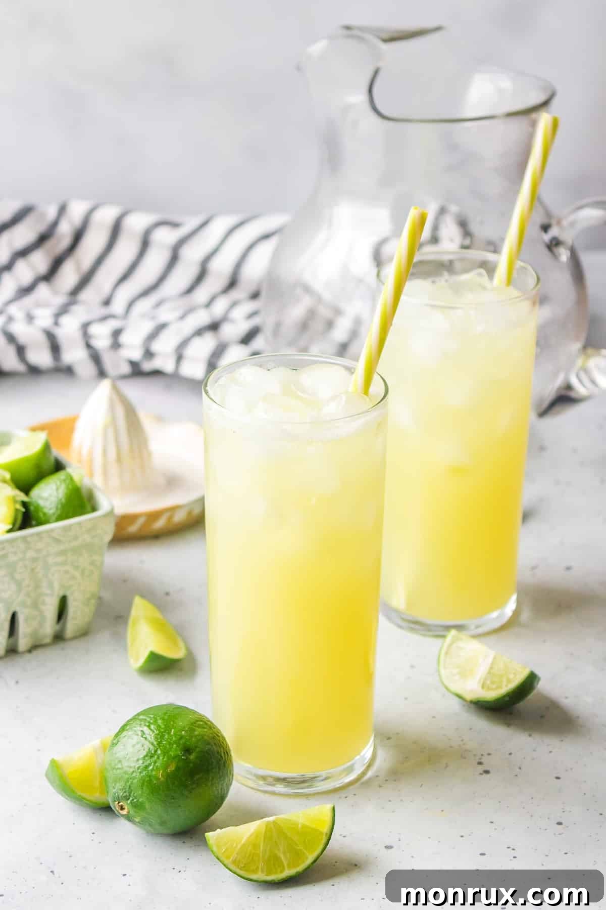 Two glasses of Pineapple Ginger Beer Mocktail, expertly garnished with lime and pineapple, complete with straws and ready to be served and enjoyed.