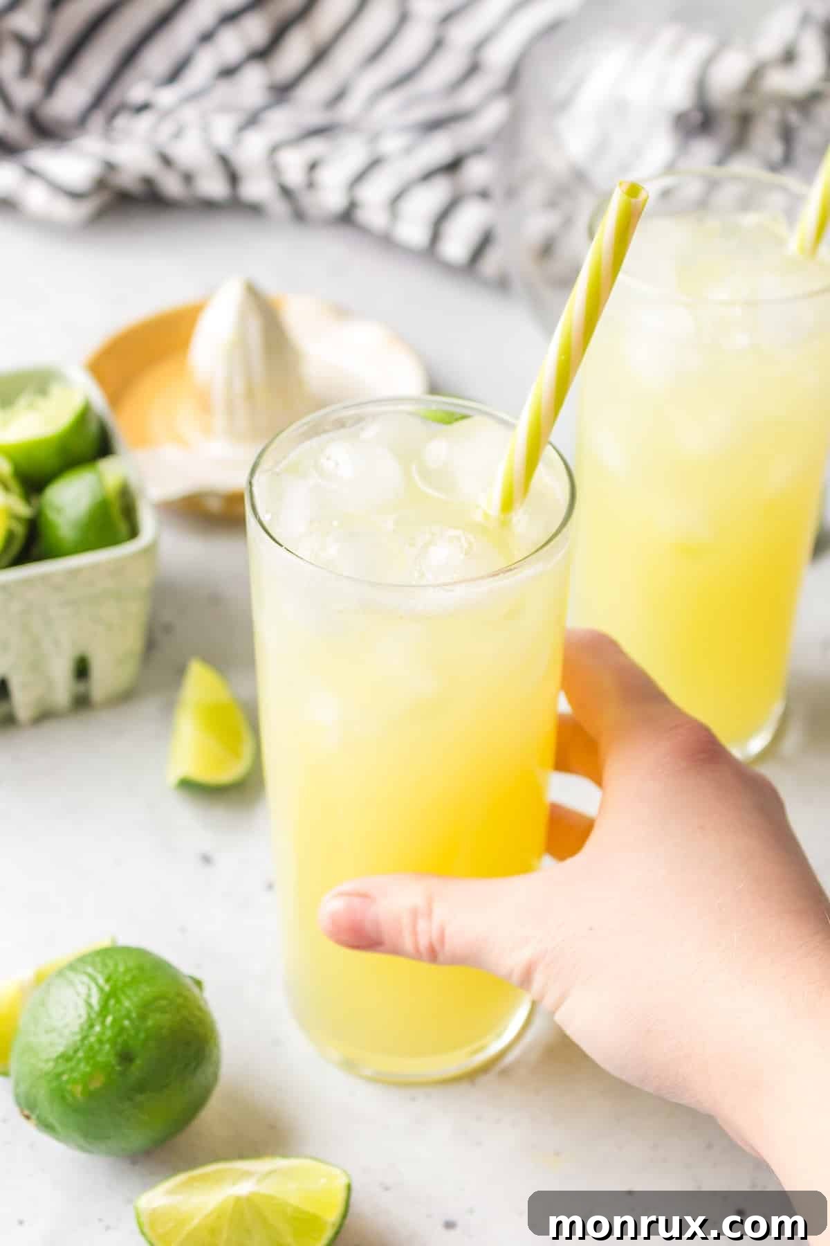 A person holding a glass of refreshing Pineapple Ginger Beer Mocktail against a bright, inviting background, ready to take a sip.