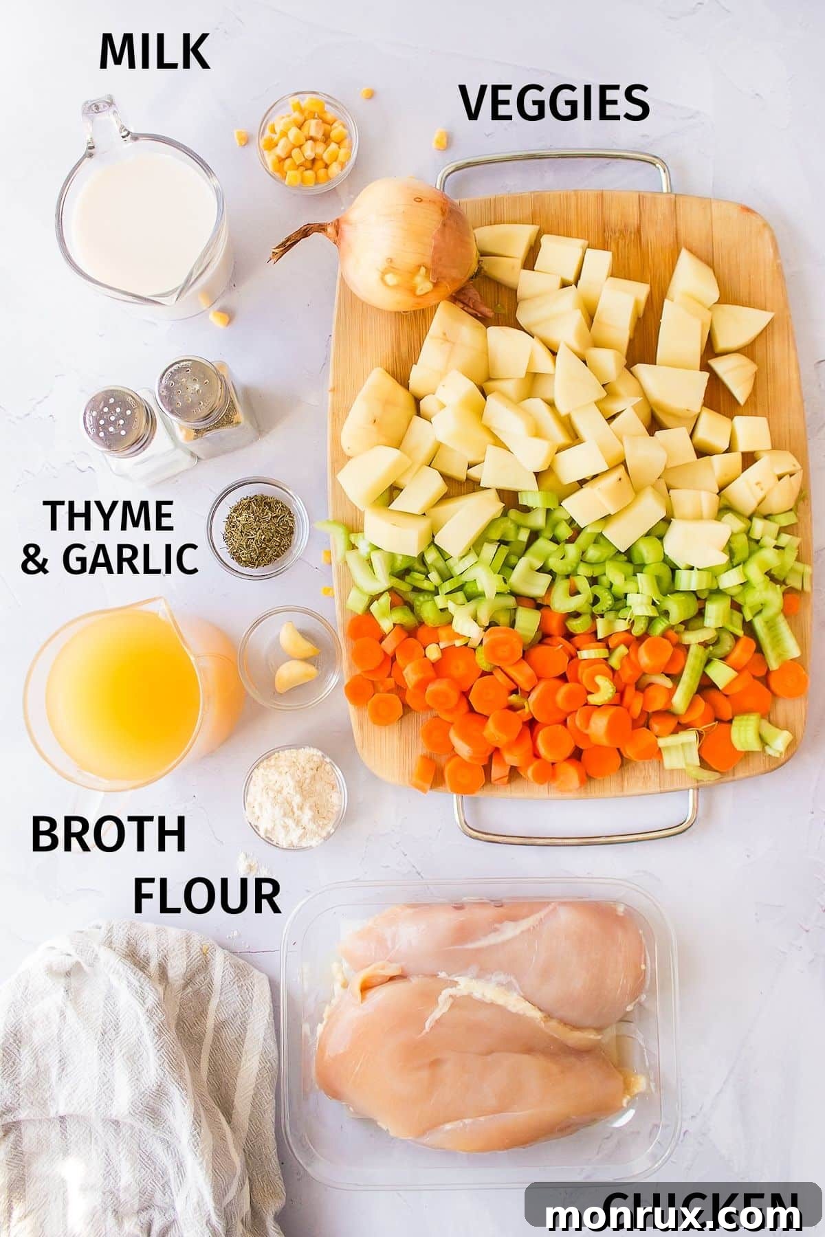 A selection of fresh ingredients laid out, including chicken breasts, corn, potatoes, carrots, celery, onion, and broth, ready for the crockpot.
