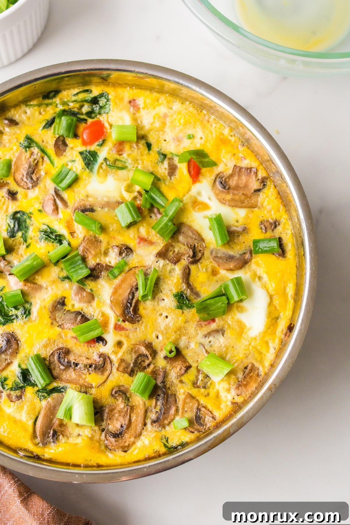 A beautifully baked vegetable frittata in a pan, ready to be served on a rustic kitchen table.