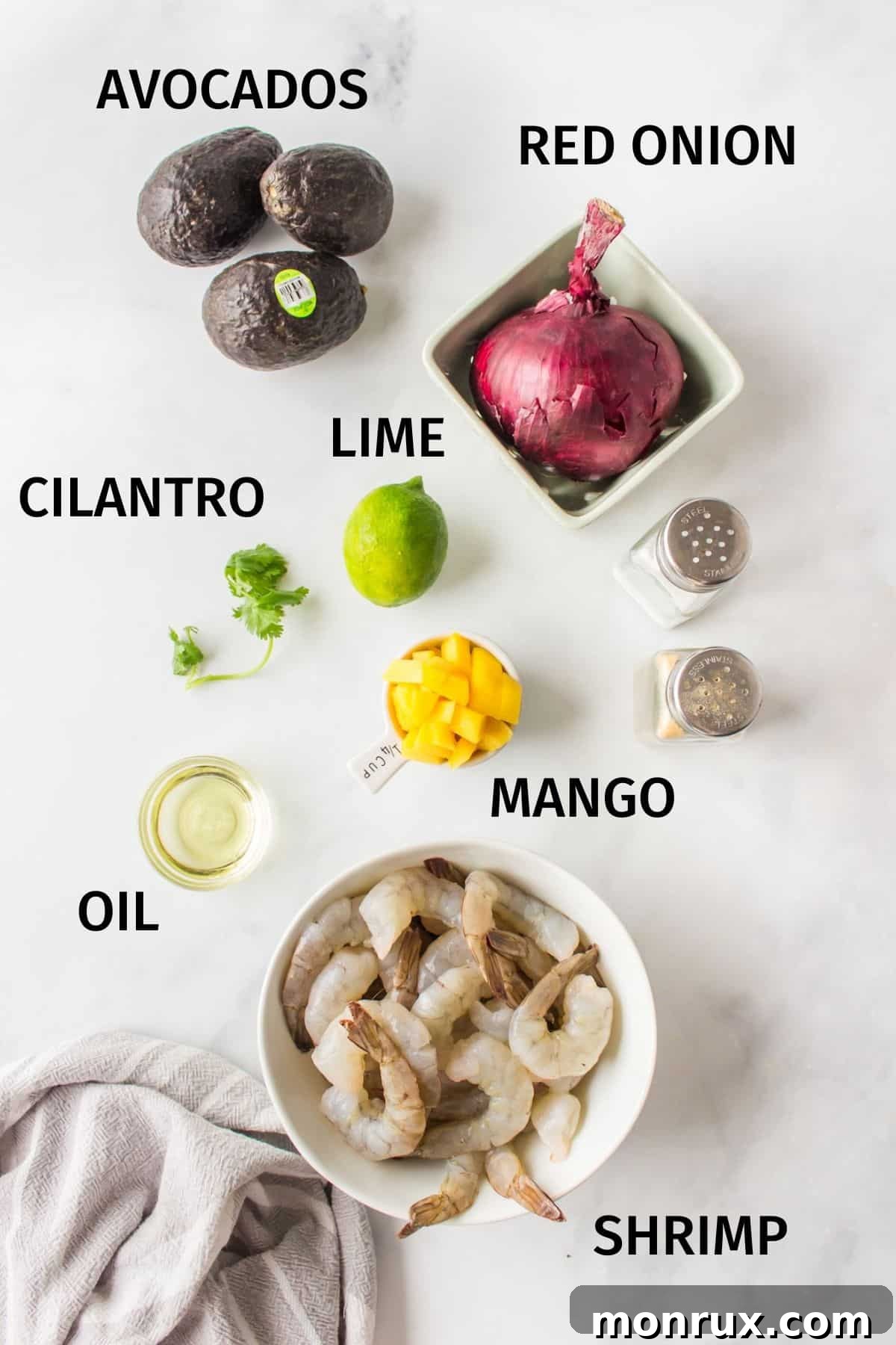 ingredients needed for avocado mango shrimp salad on a counter, including fresh shrimp, mango, avocado, and lime.