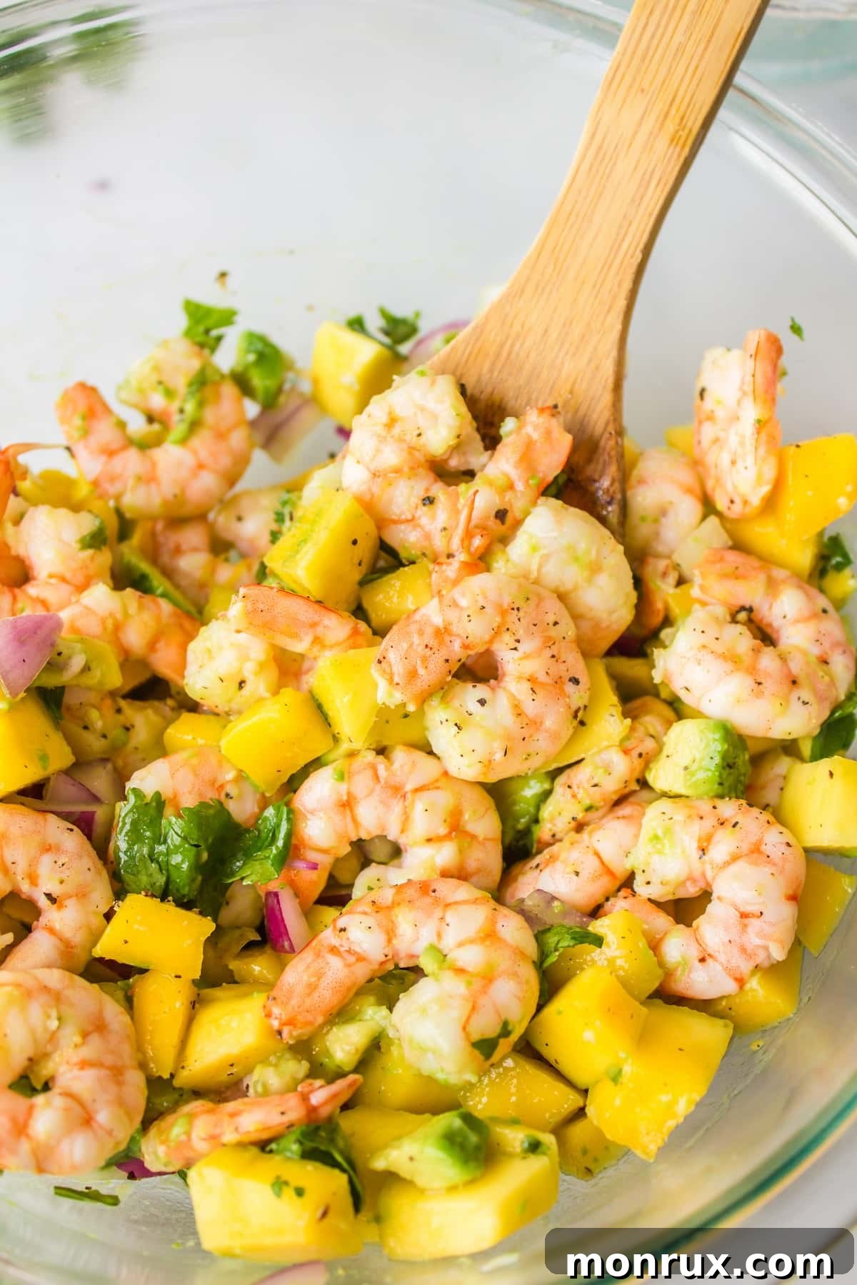 a spoon full of avocado mango shrimp salad, ready to be eaten.