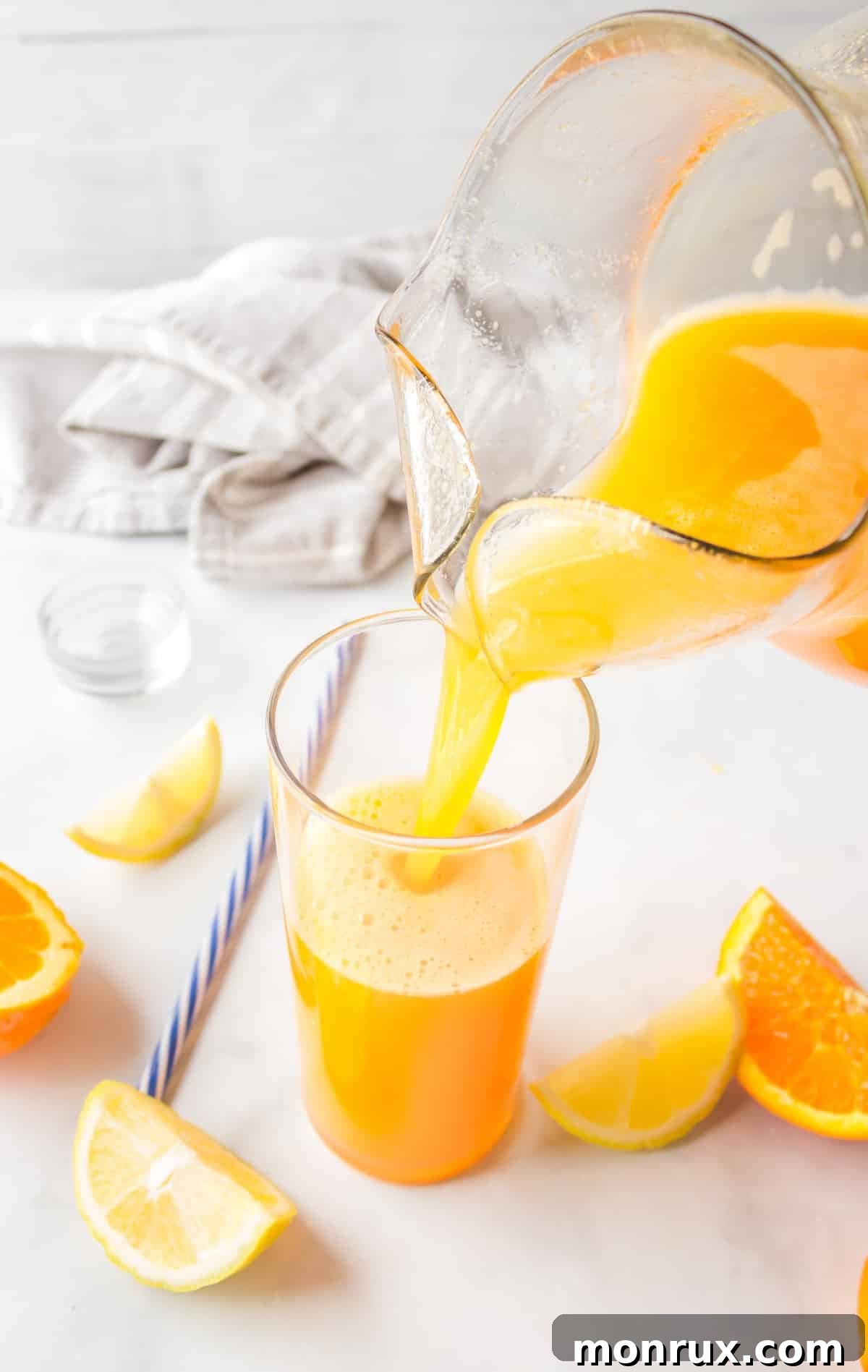 Vibrant yellow juice being poured from a pitcher into a glass, ready to be enjoyed.