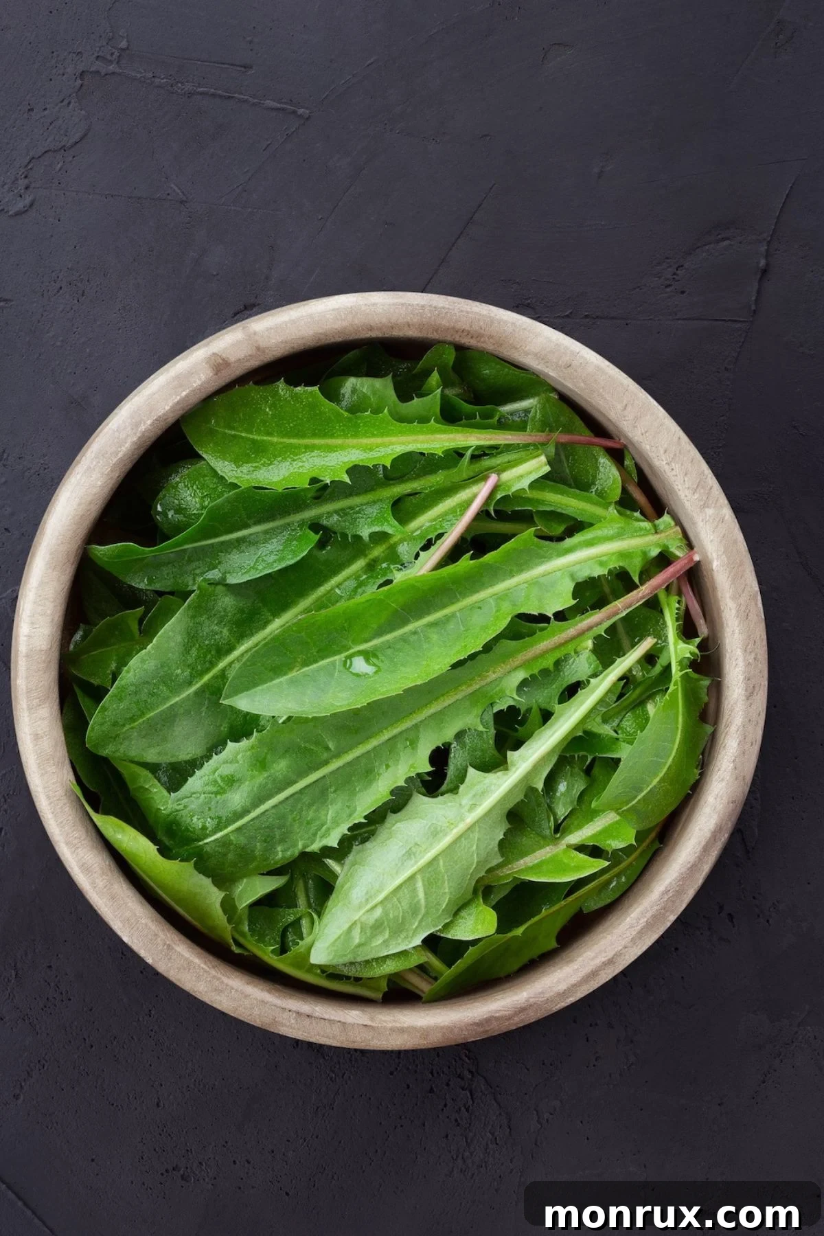 A bowl filled with fresh, vibrant dandelion greens, ready for juicing.
