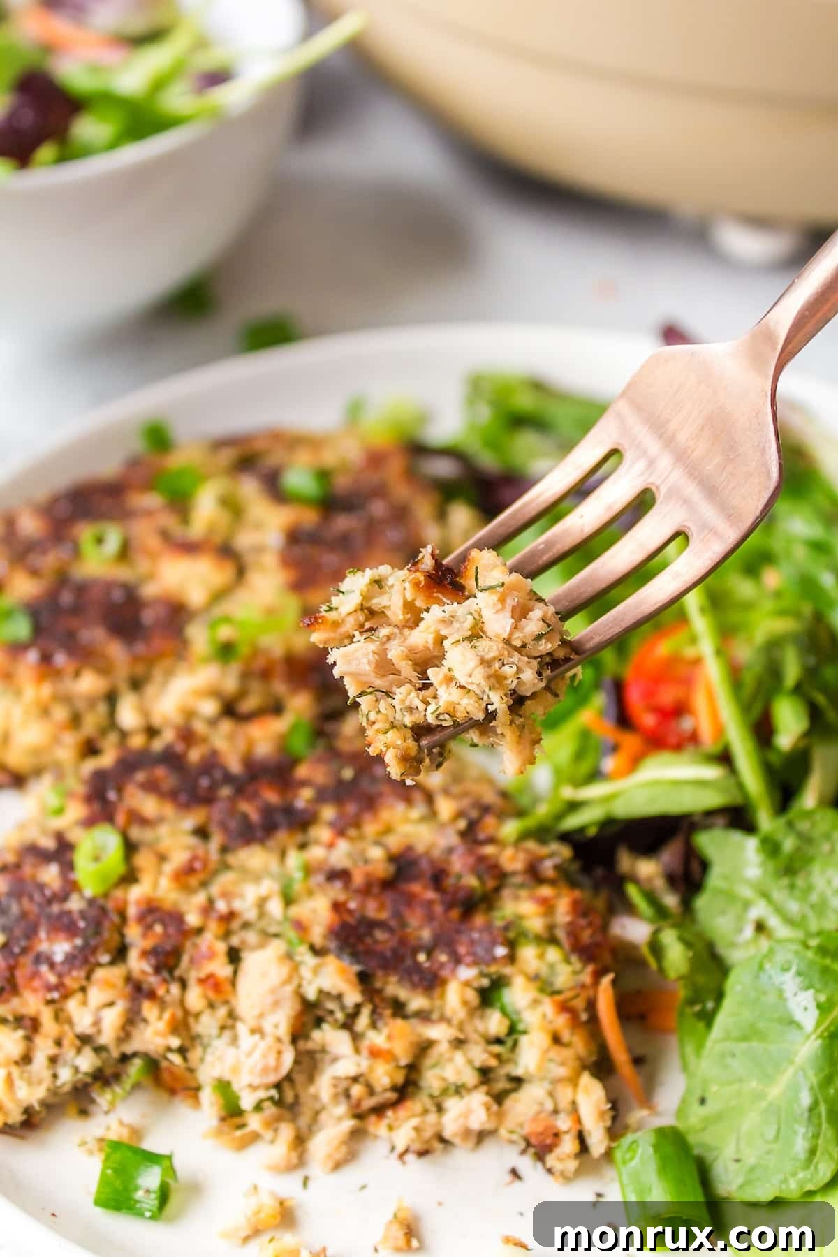 A perfectly cooked gluten-free salmon cake being lifted on a fork, showing its golden-brown crust.
