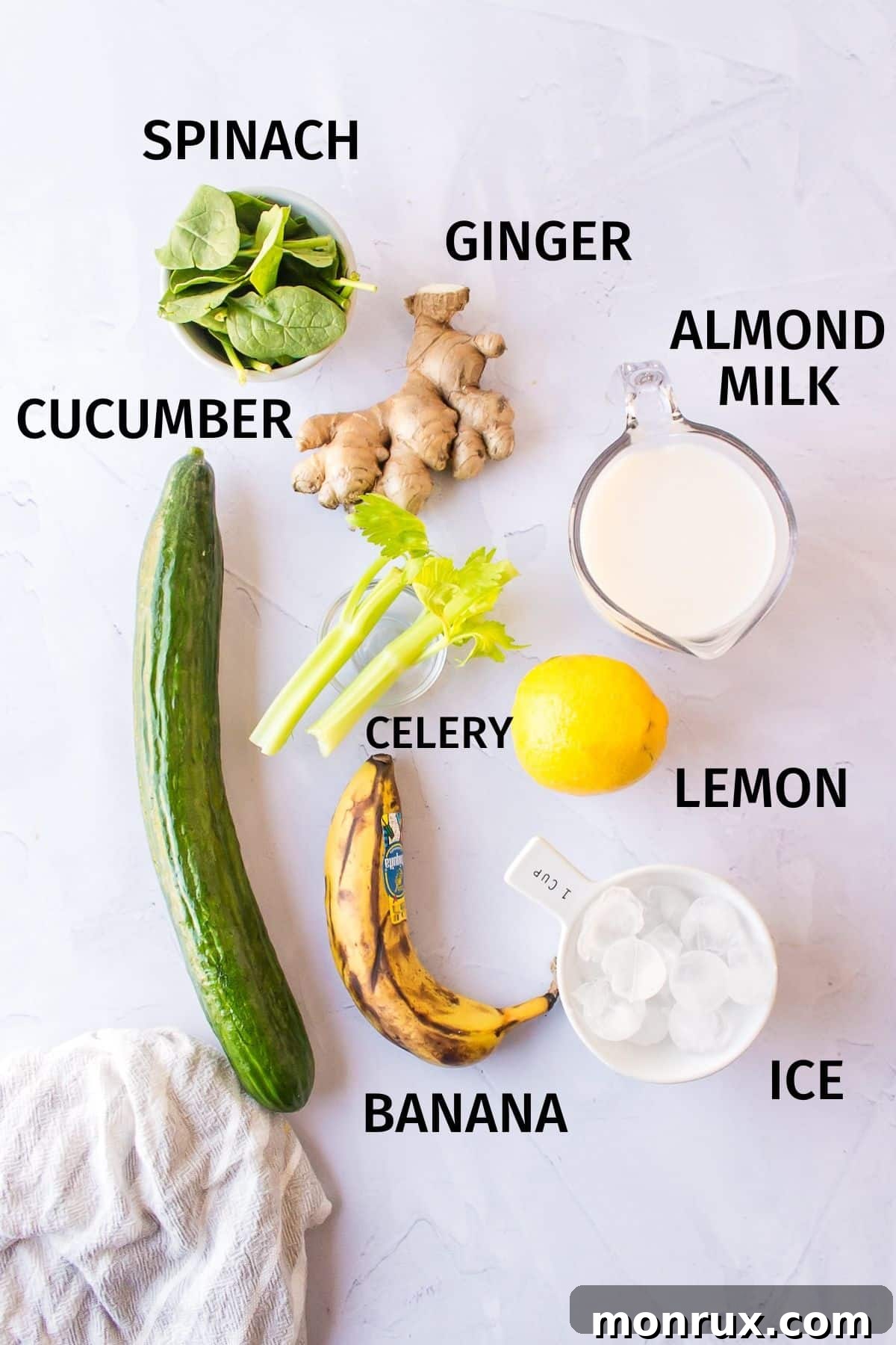 Ingredients for a celery cucumber smoothie laid out on a kitchen counter, including celery stalks, cucumbers, spinach, banana, ginger, and almond milk.