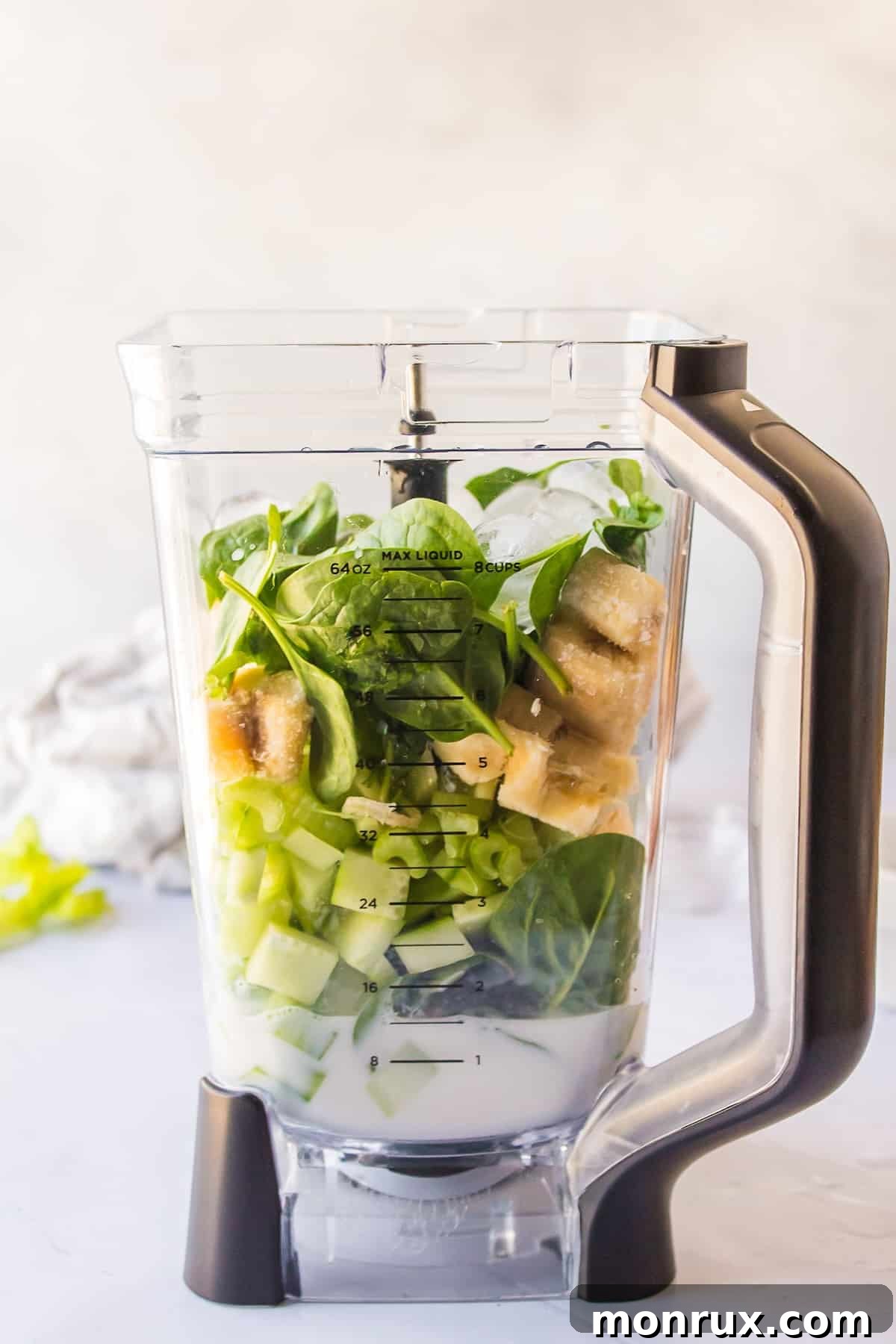 Various ingredients for a celery cucumber smoothie placed inside a high-speed blender, ready for blending.