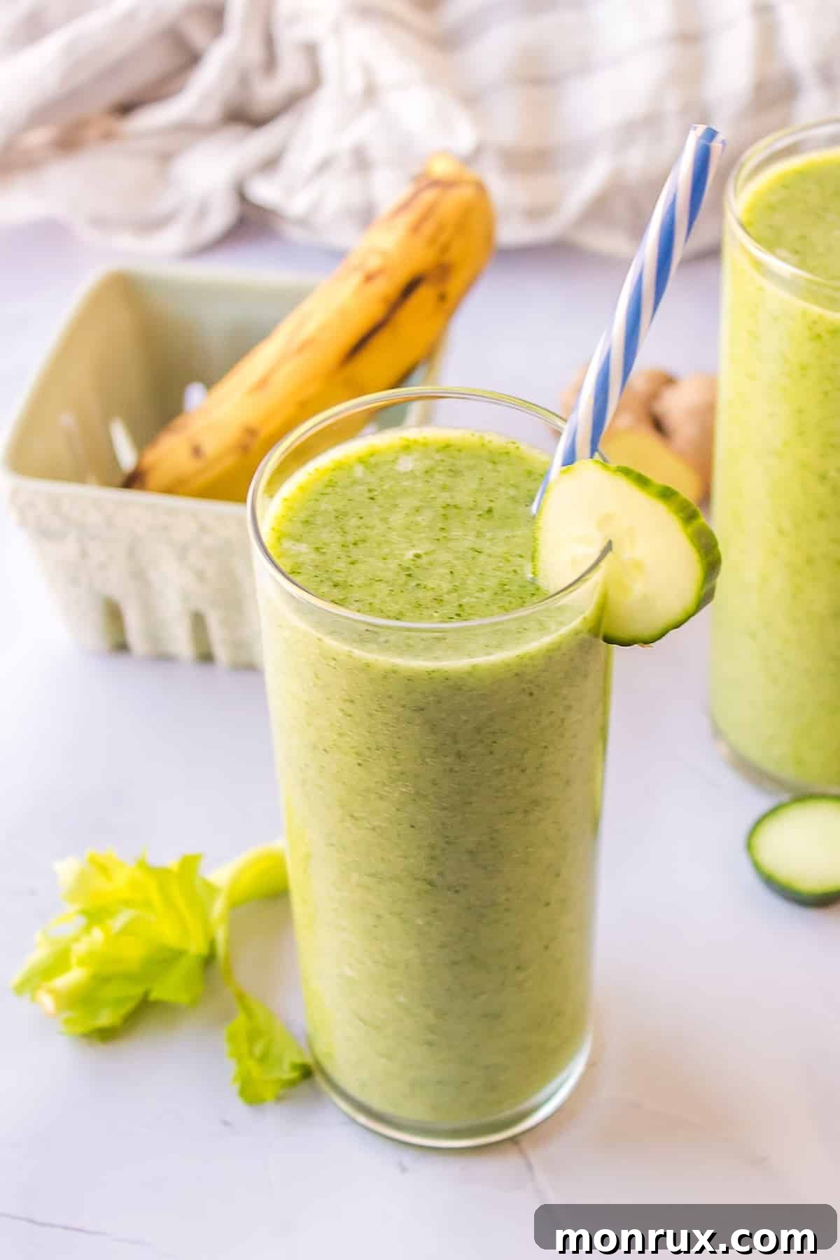 A single glass of vibrant green celery cucumber smoothie, ready to be enjoyed, with a subtle garnish.