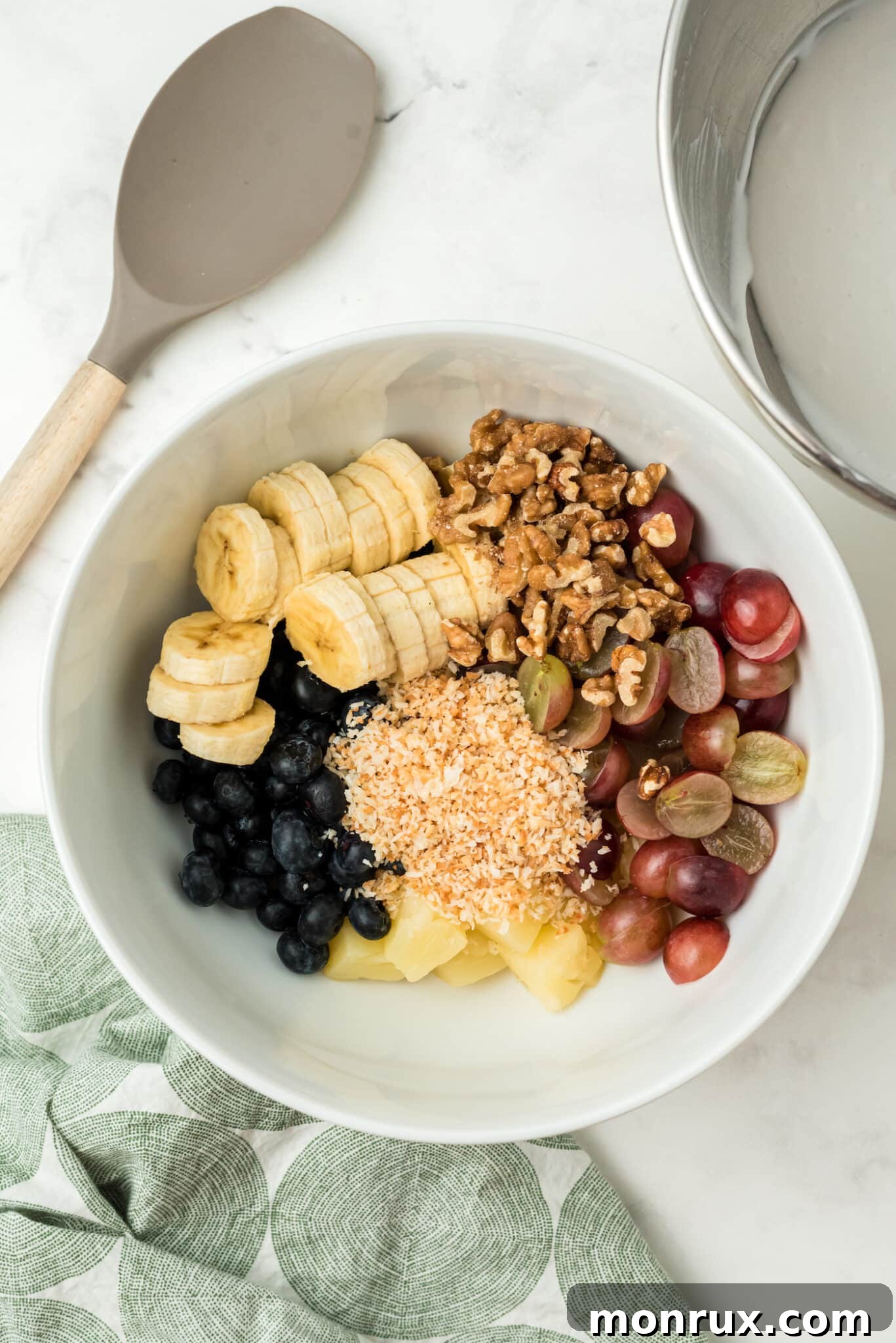 A smaller mixing bowl containing coconut cream and vanilla extract, ready to be whipped into a dairy-free dressing.
