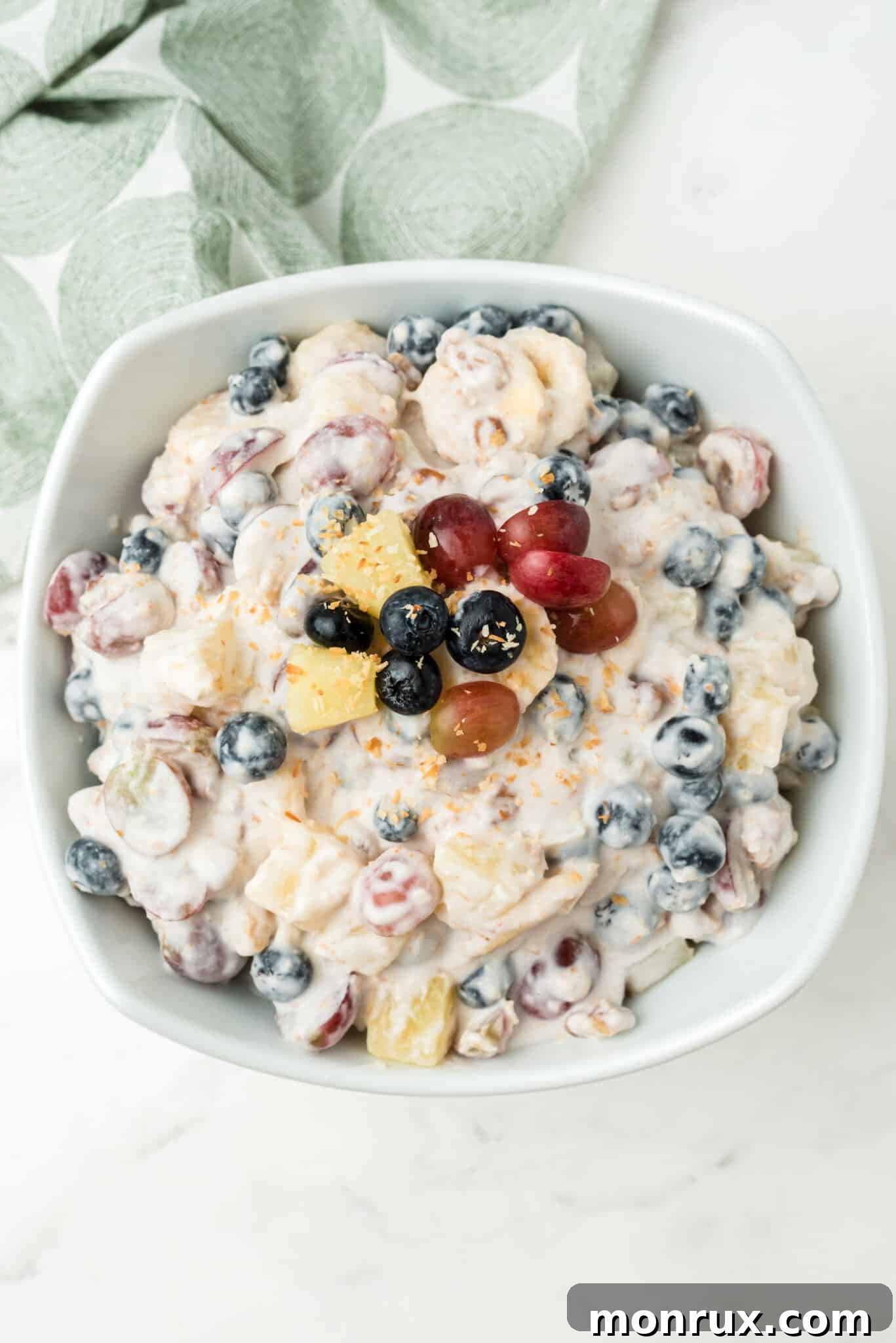A beautifully arranged serving bowl showcasing the finished vegan ambrosia salad, garnished and ready to be enjoyed.