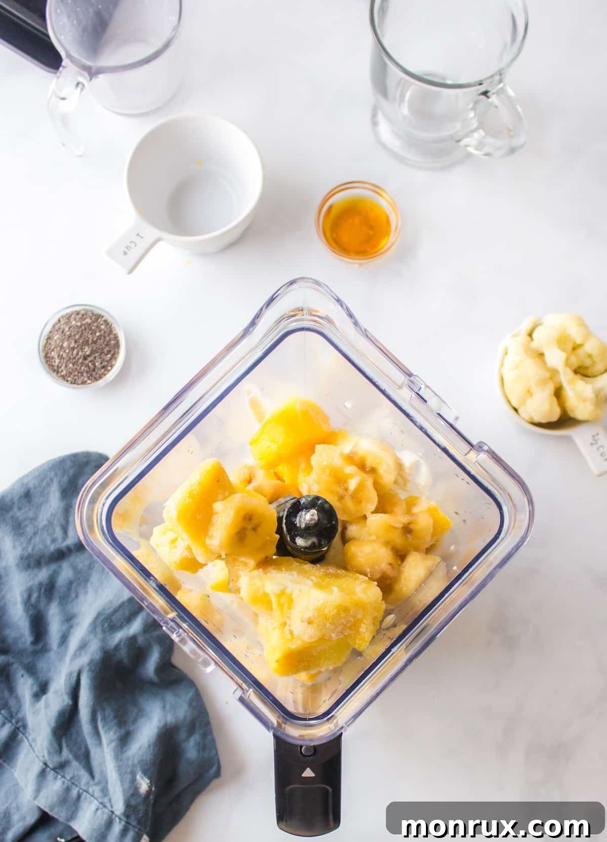 Almond milk, Greek yogurt, pineapple, and banana added to a blender for a smoothie.