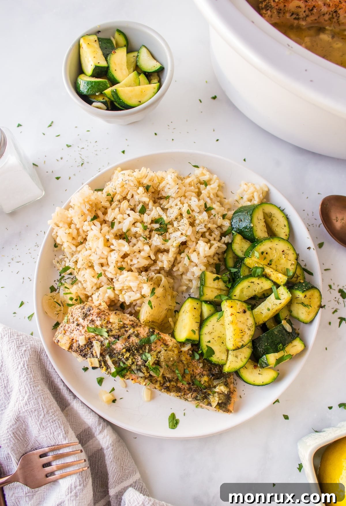 Slow cooker salmon served on a plate with fluffy white rice and steamed green vegetables, garnished with fresh dill and lemon slices.