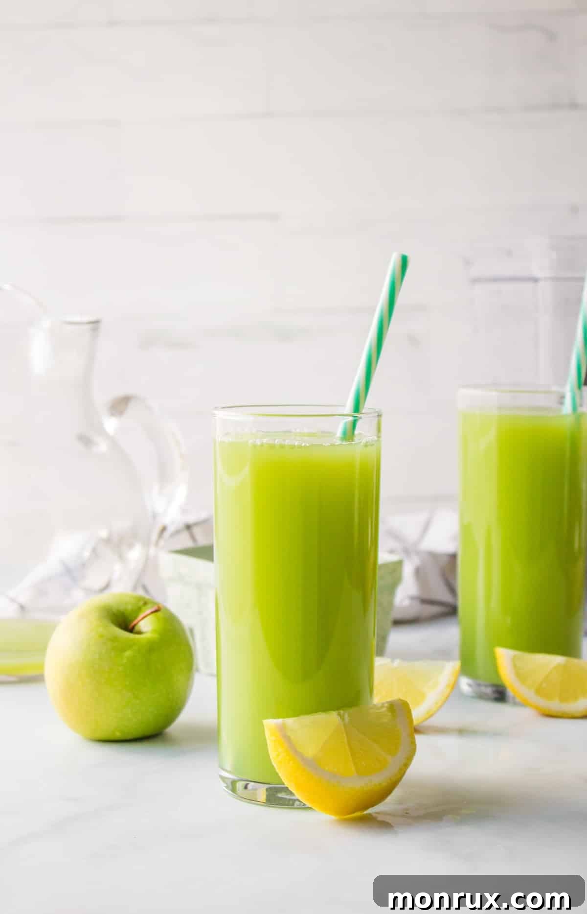 two glasses of cucumber apple juice with straws.