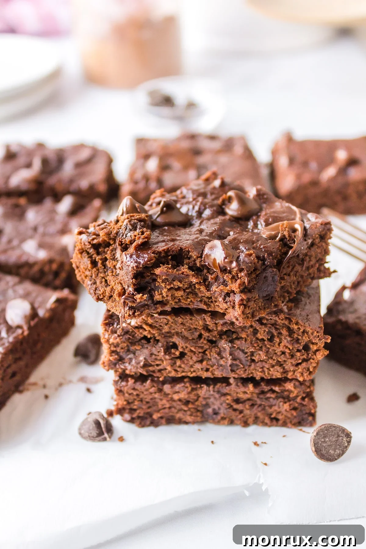 Stack of rich, fudgy gluten-free and dairy-free brownies on a rustic wooden table, garnished with a sprinkle of powdered sugar, inviting a delightful indulgence.