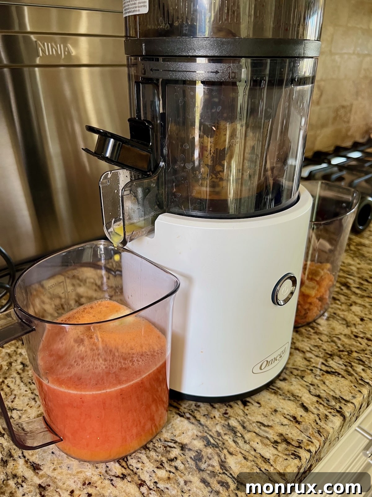 A close-up shot of a juicer in action, extracting fresh strawberry and orange juice.