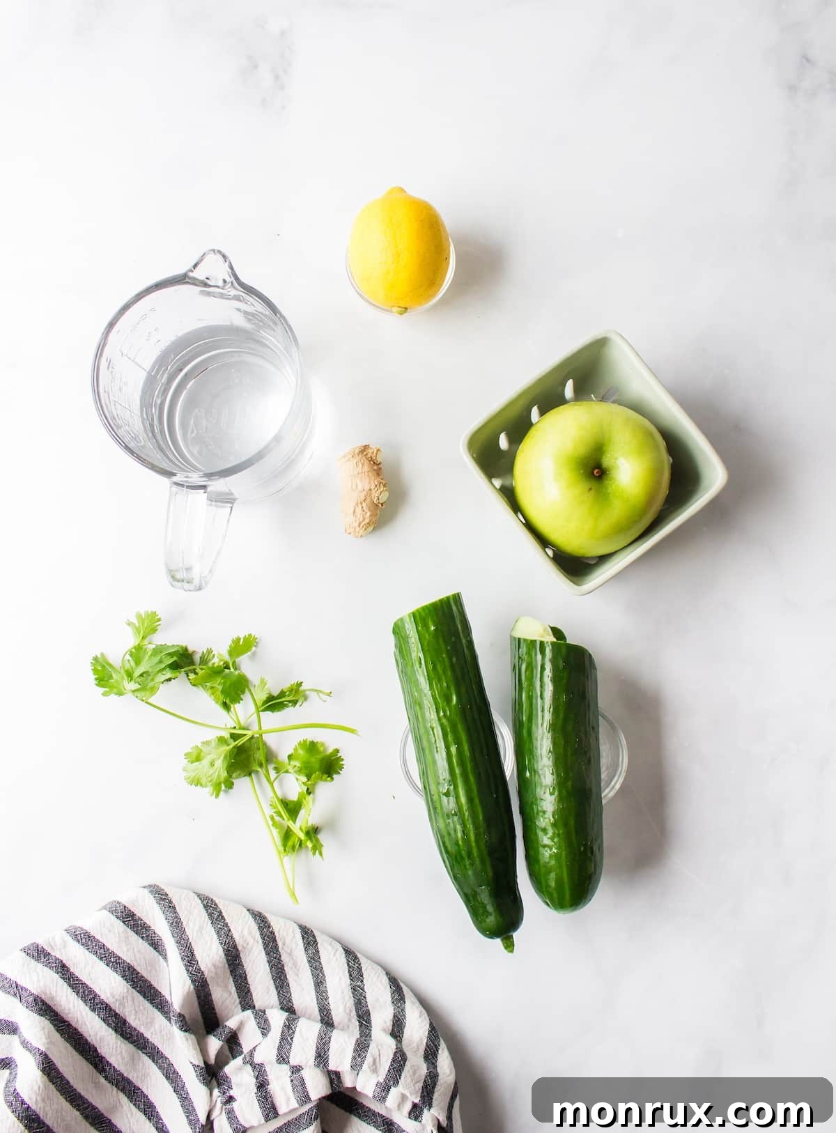 Ingredients for cilantro juice laid out on a table: cucumber, lemon, cilantro, and ginger.