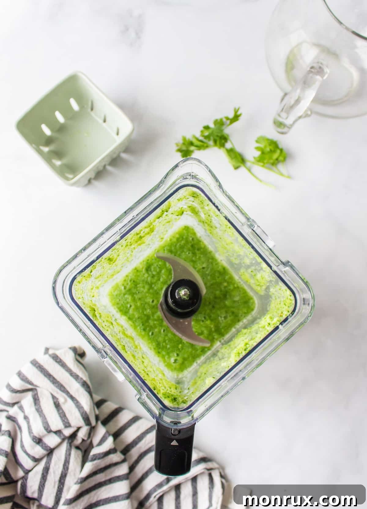 Blender filled with cilantro, cucumber, lemon, and ginger, ready to be blended.