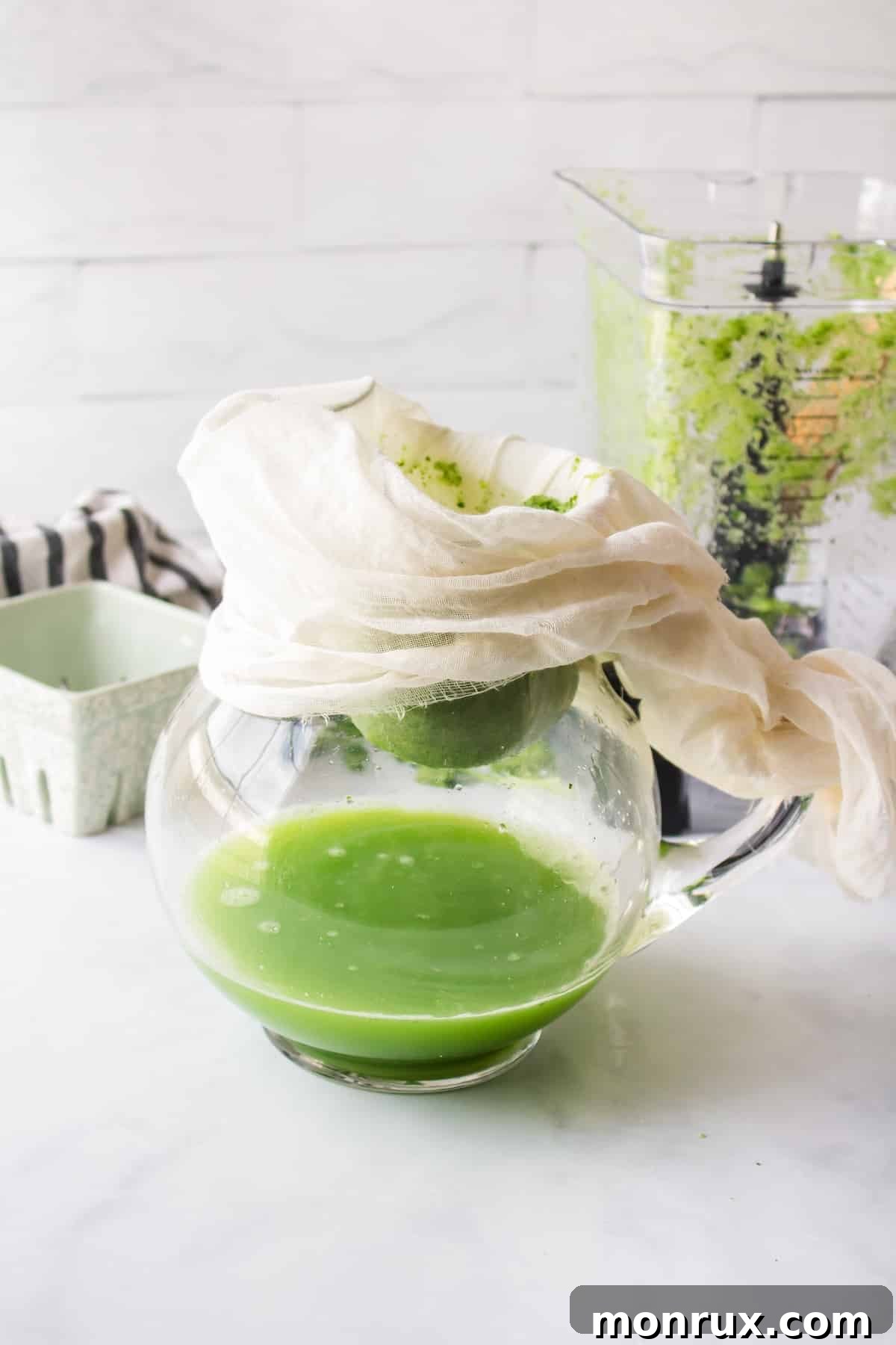 Straining blended cilantro juice through a nut milk bag to separate pulp.